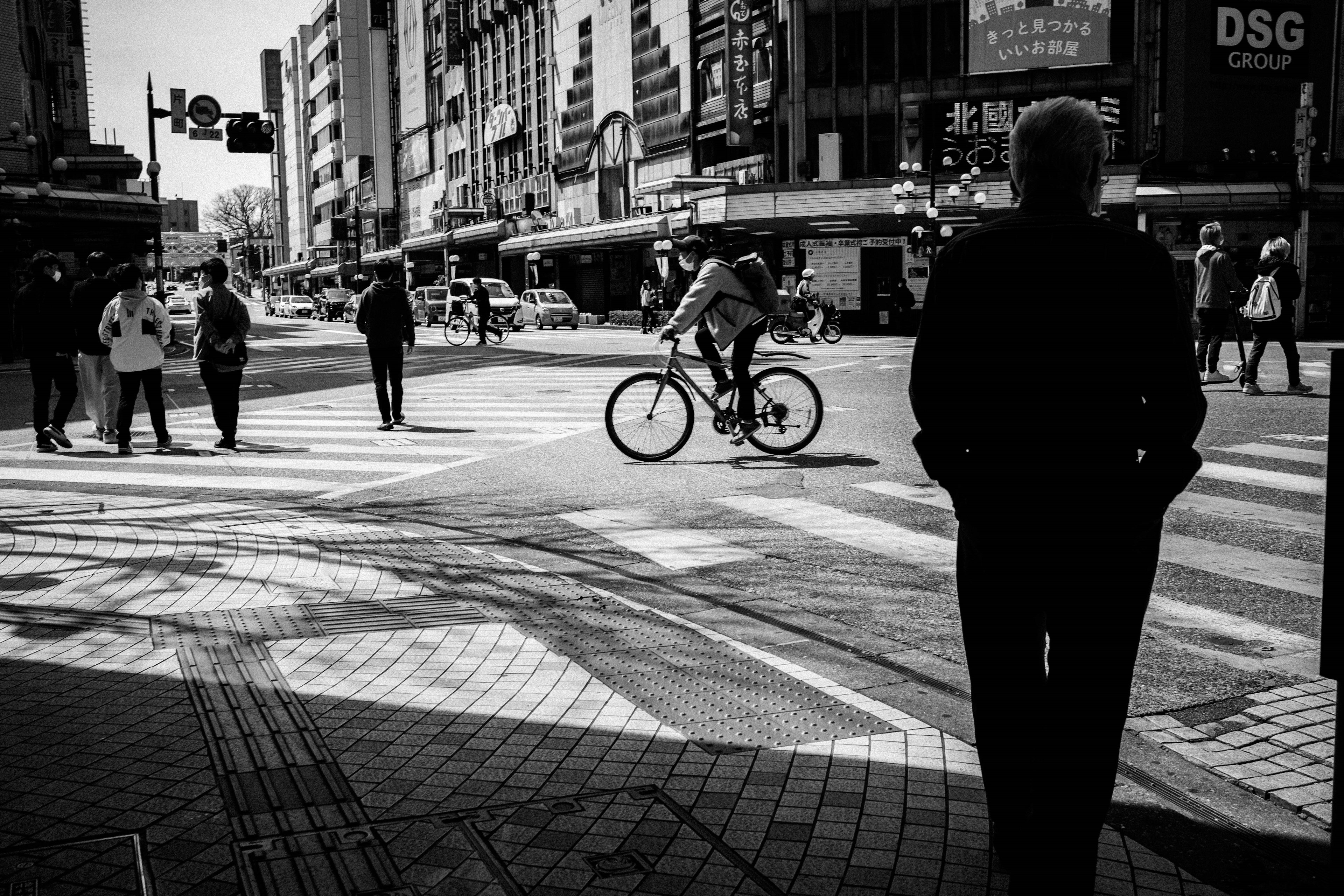 Una escena de calle en blanco y negro con un ciclista y peatones