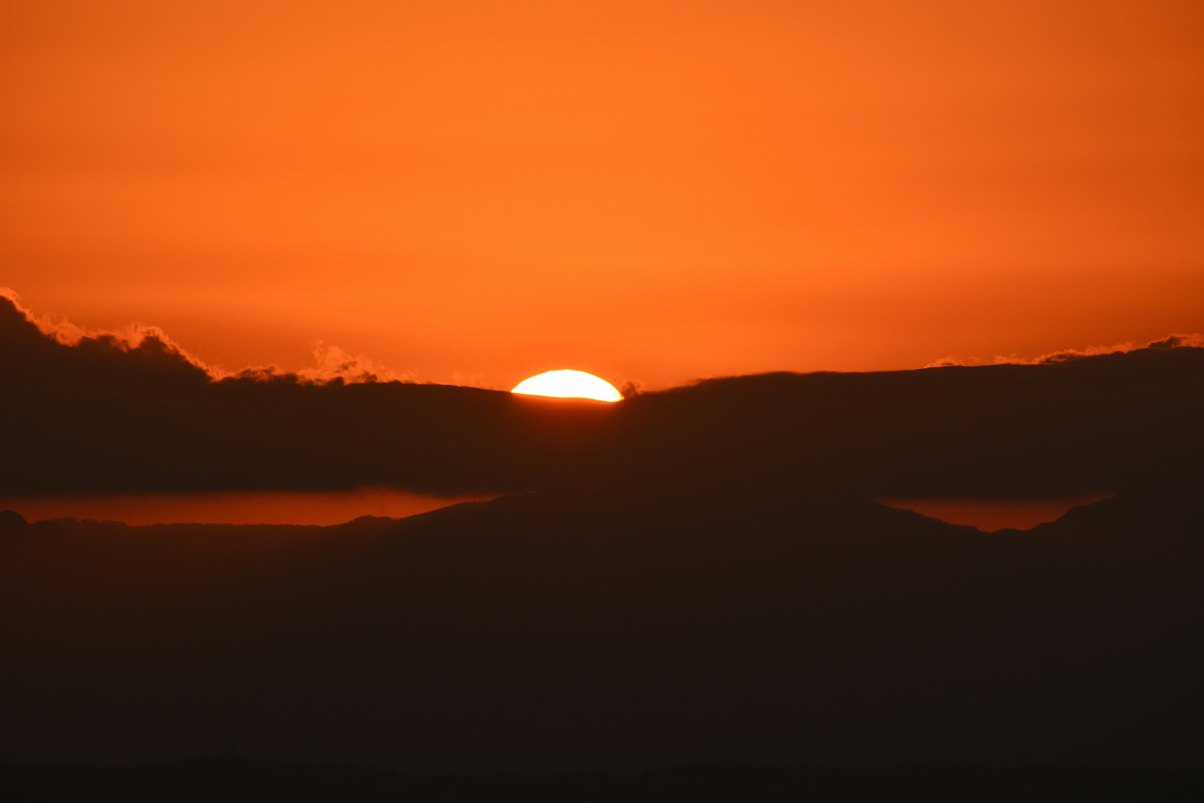 夕日が山の間から沈む情景