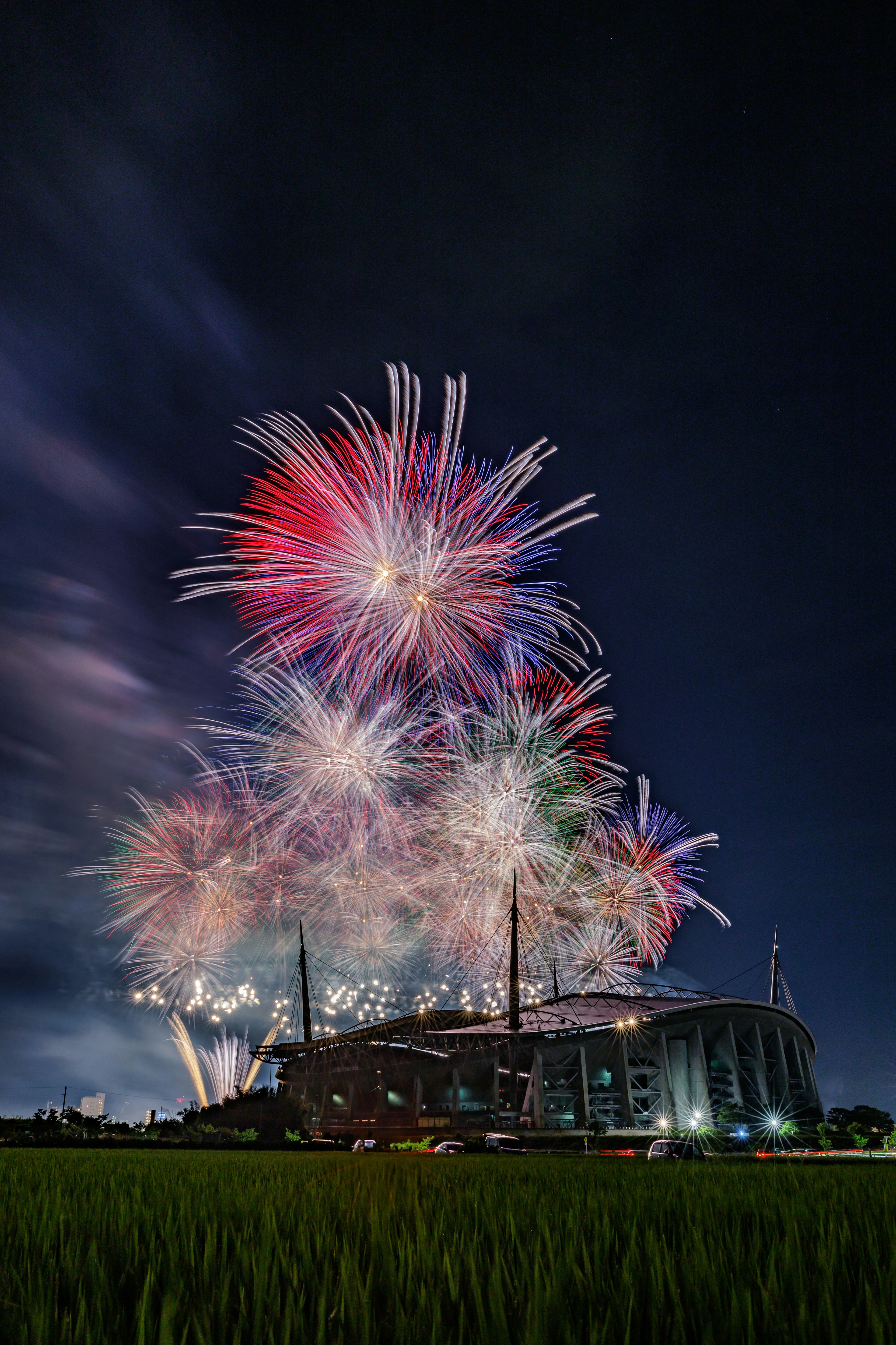 夜空に輝くカラフルな花火とスタジアムの光景