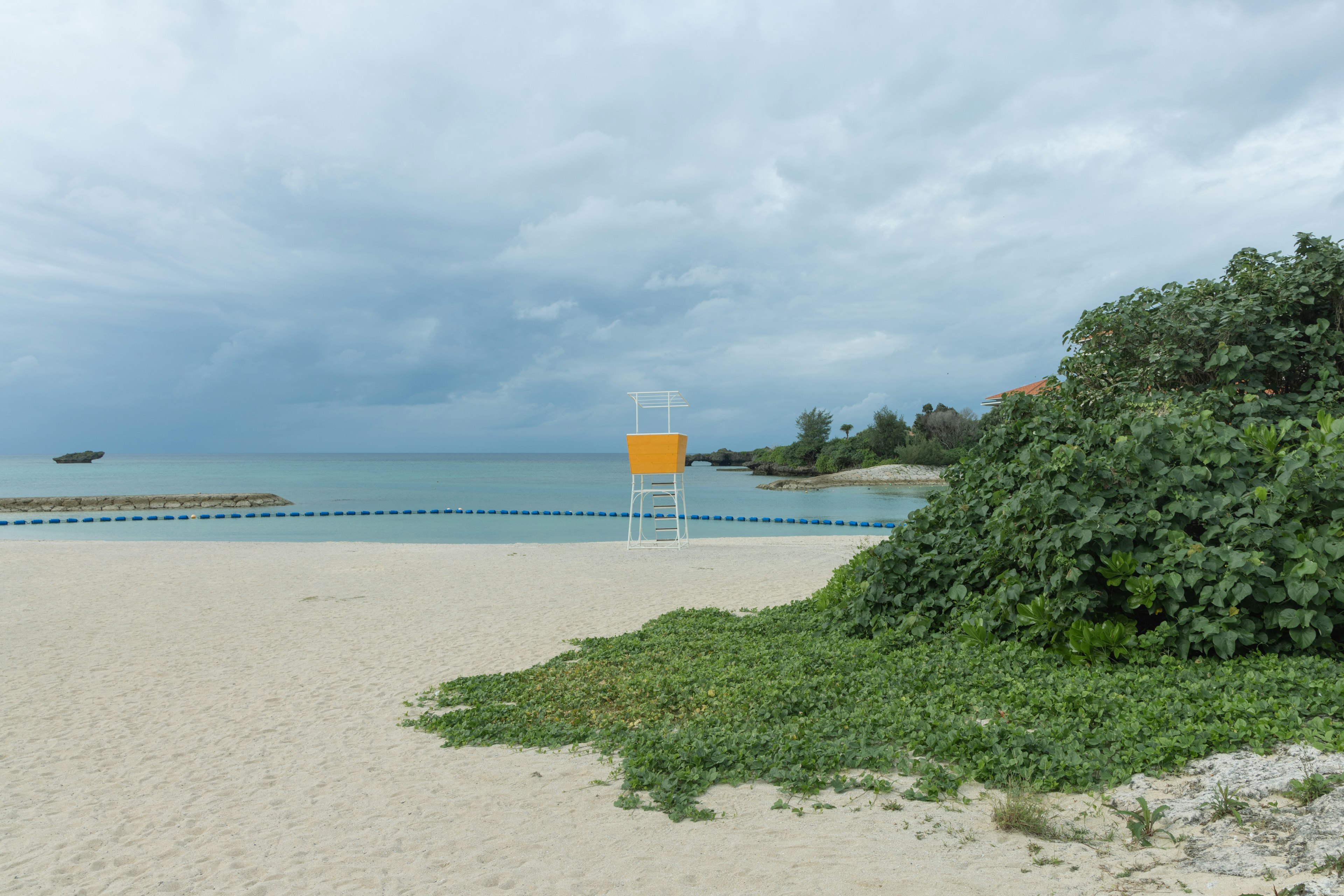 ฉากชายหาดที่มีหอคอยชีวิตสีเหลืองและทะเลสงบ