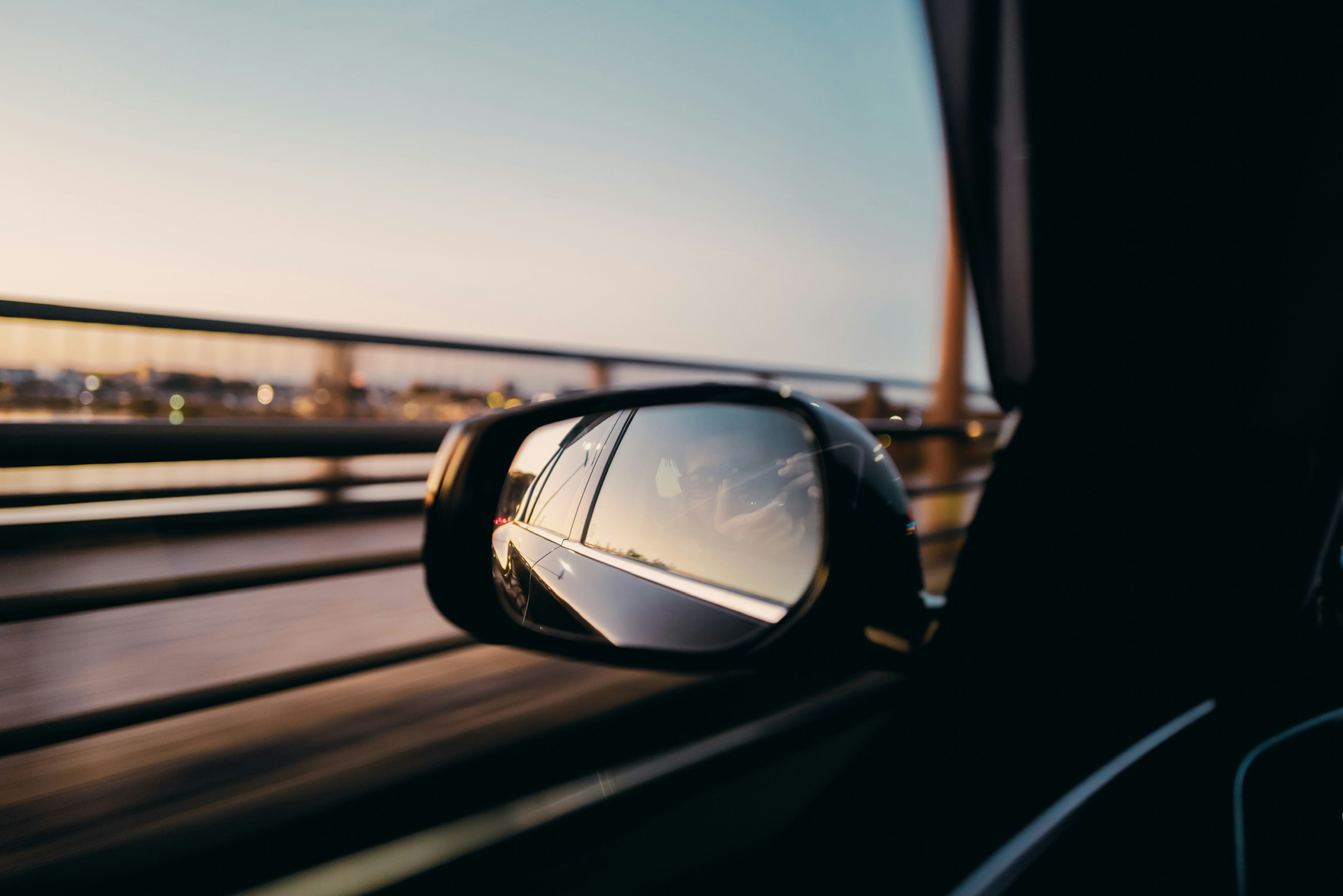 Reflection of a cityscape and sunset sky in a car side mirror