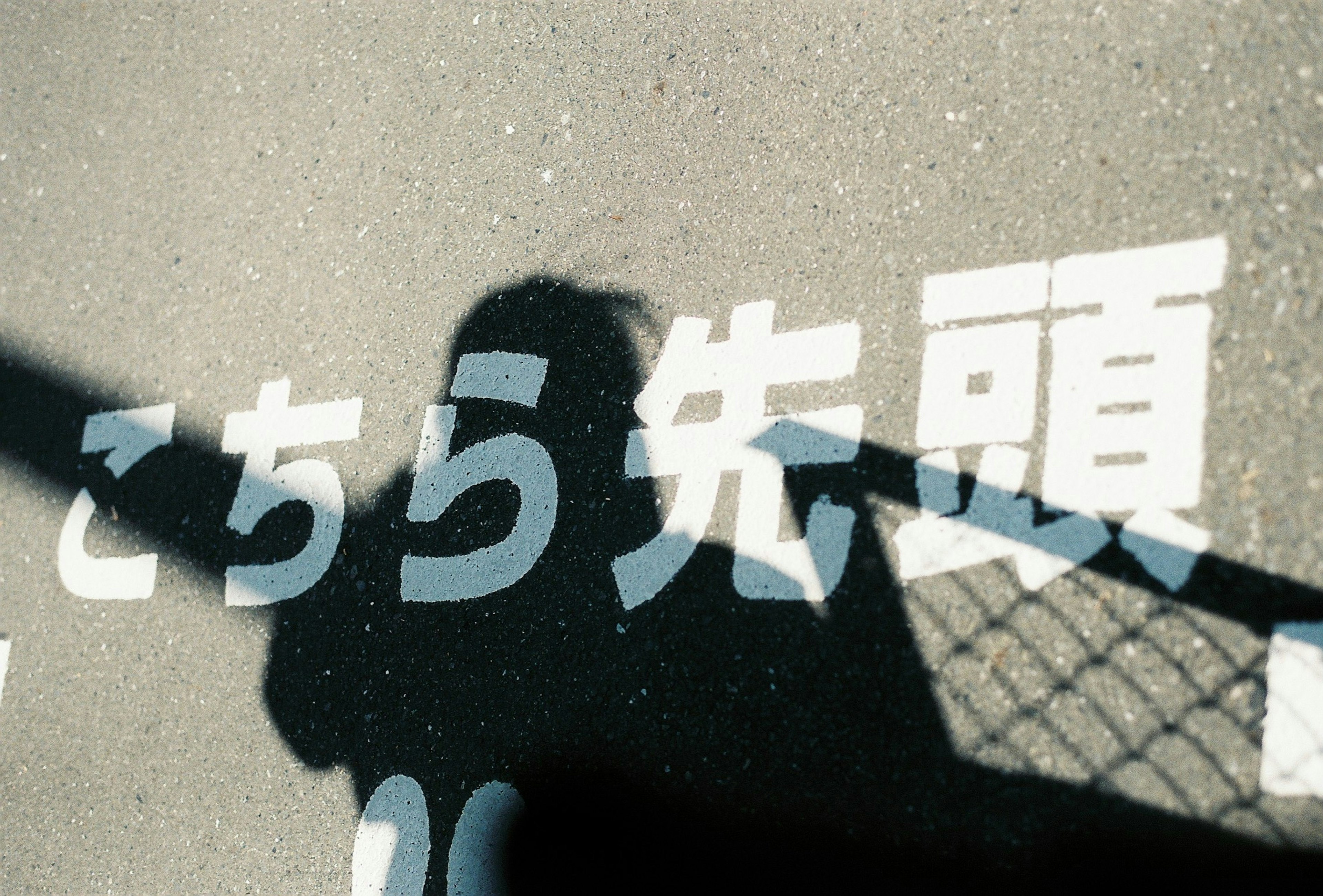 Shadow and Japanese text on the ground