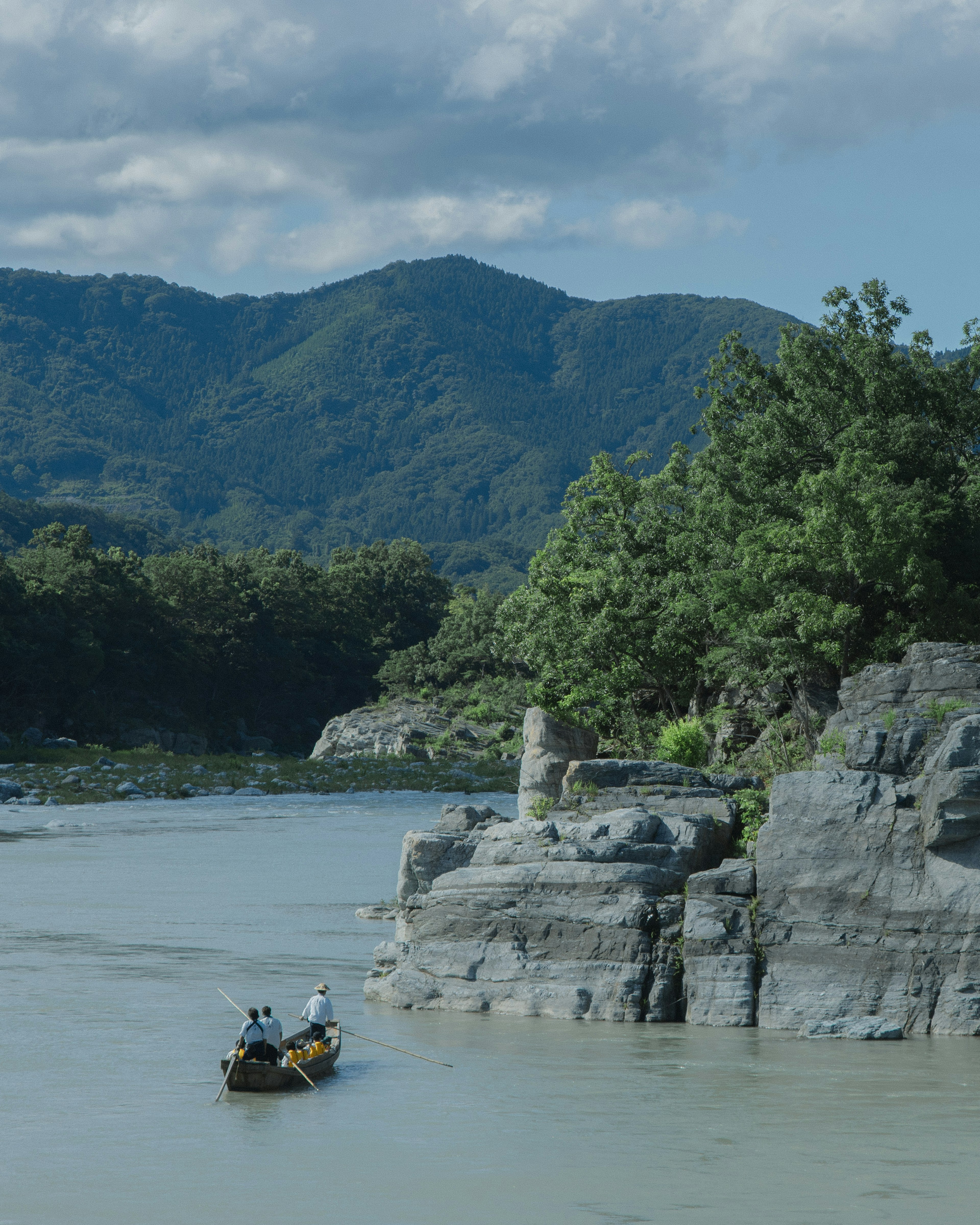 Zwei Fischer rudern auf einem Fluss mit einer malerischen Berglandschaft