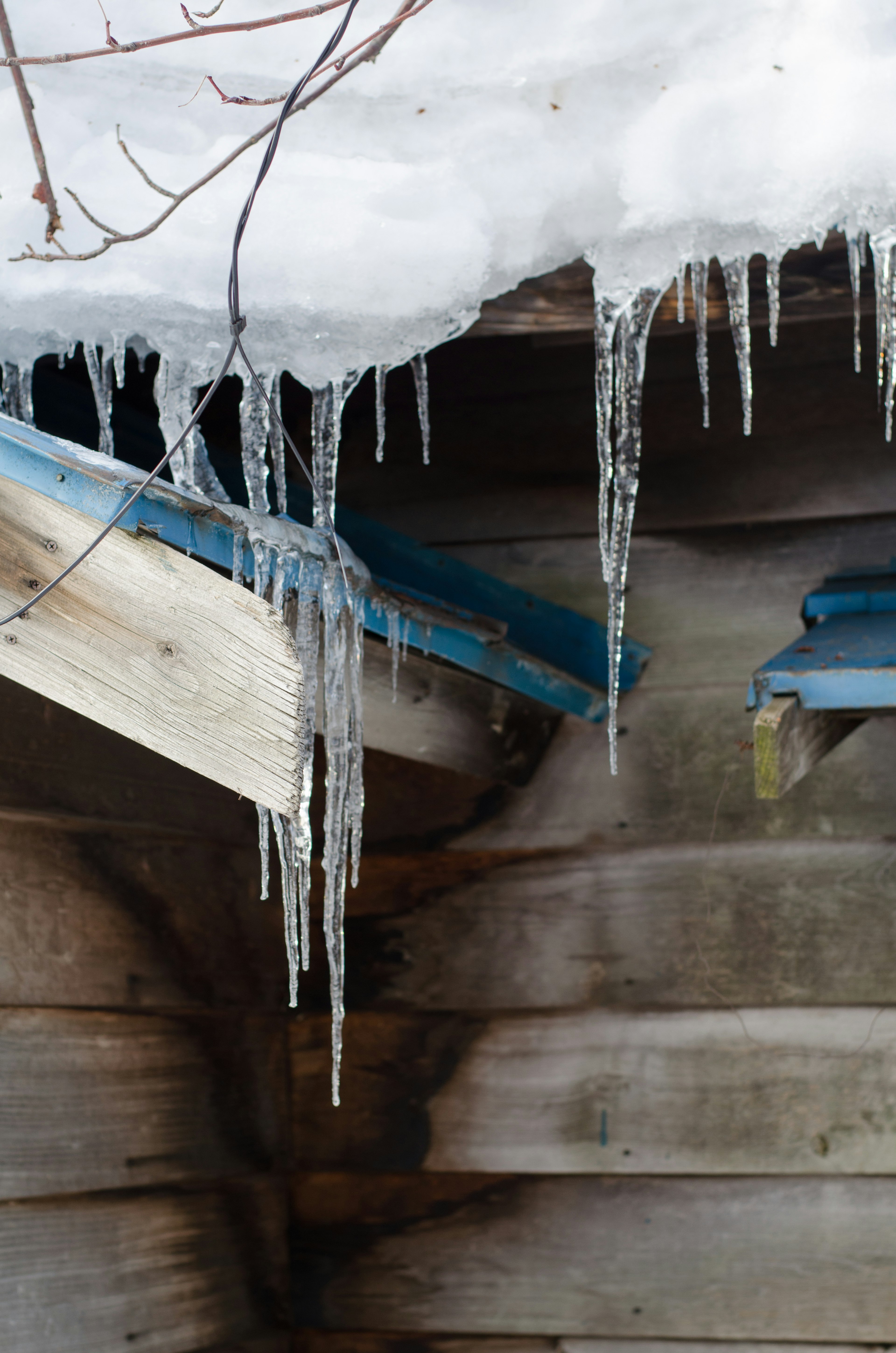 Eiszapfen hängen von einem schneebedeckten Dach einer Holzhütte