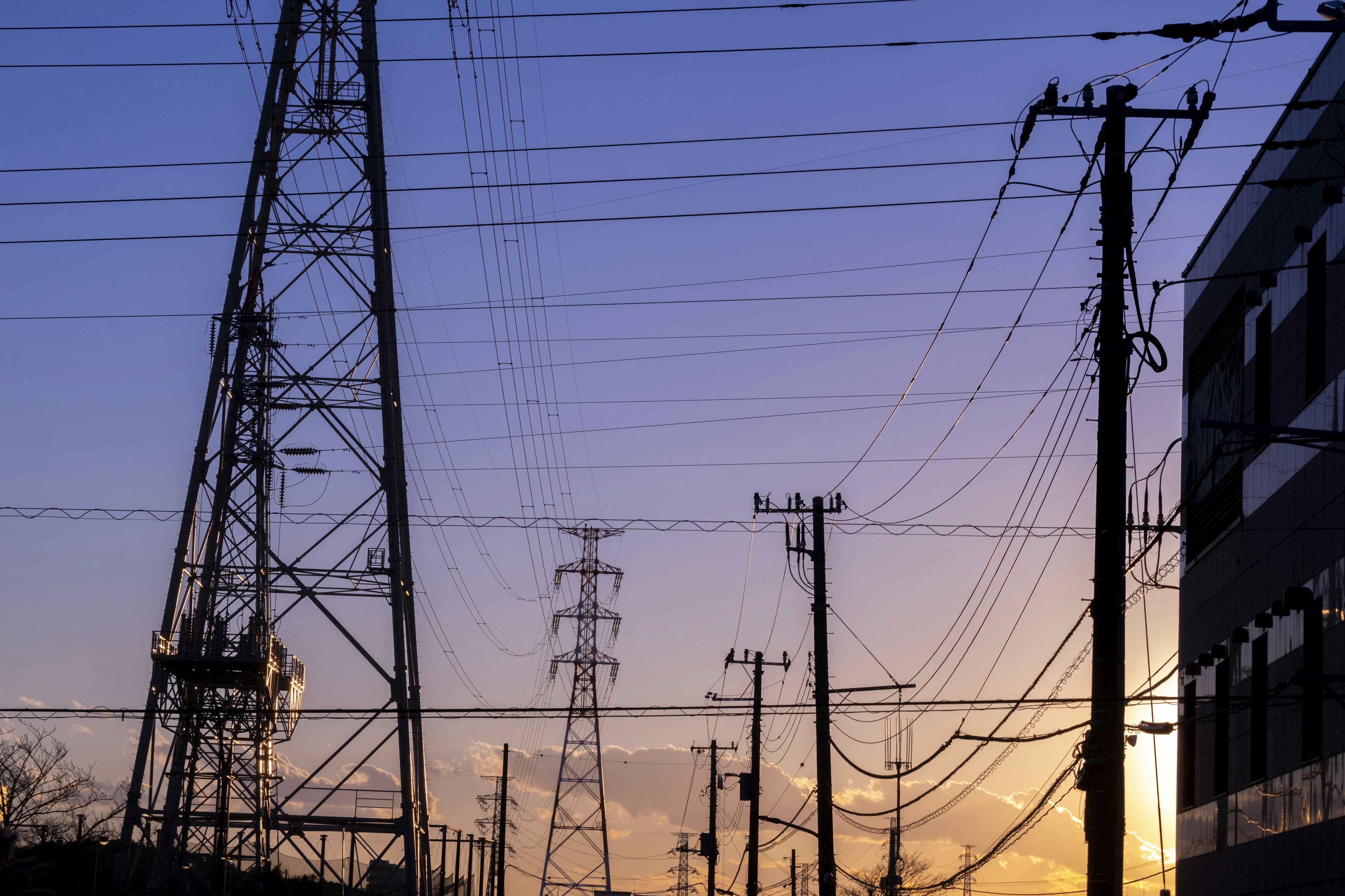 Silhouette of power lines and poles at sunset