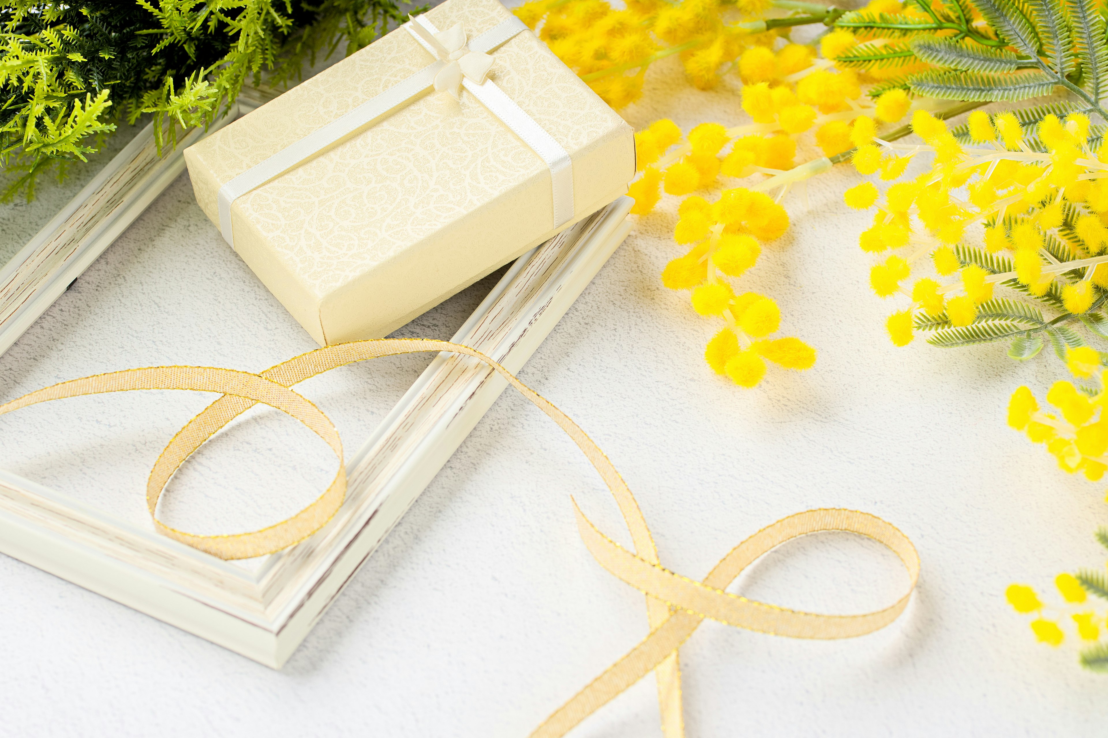 Beautiful arrangement featuring a yellow flower and a white gift box