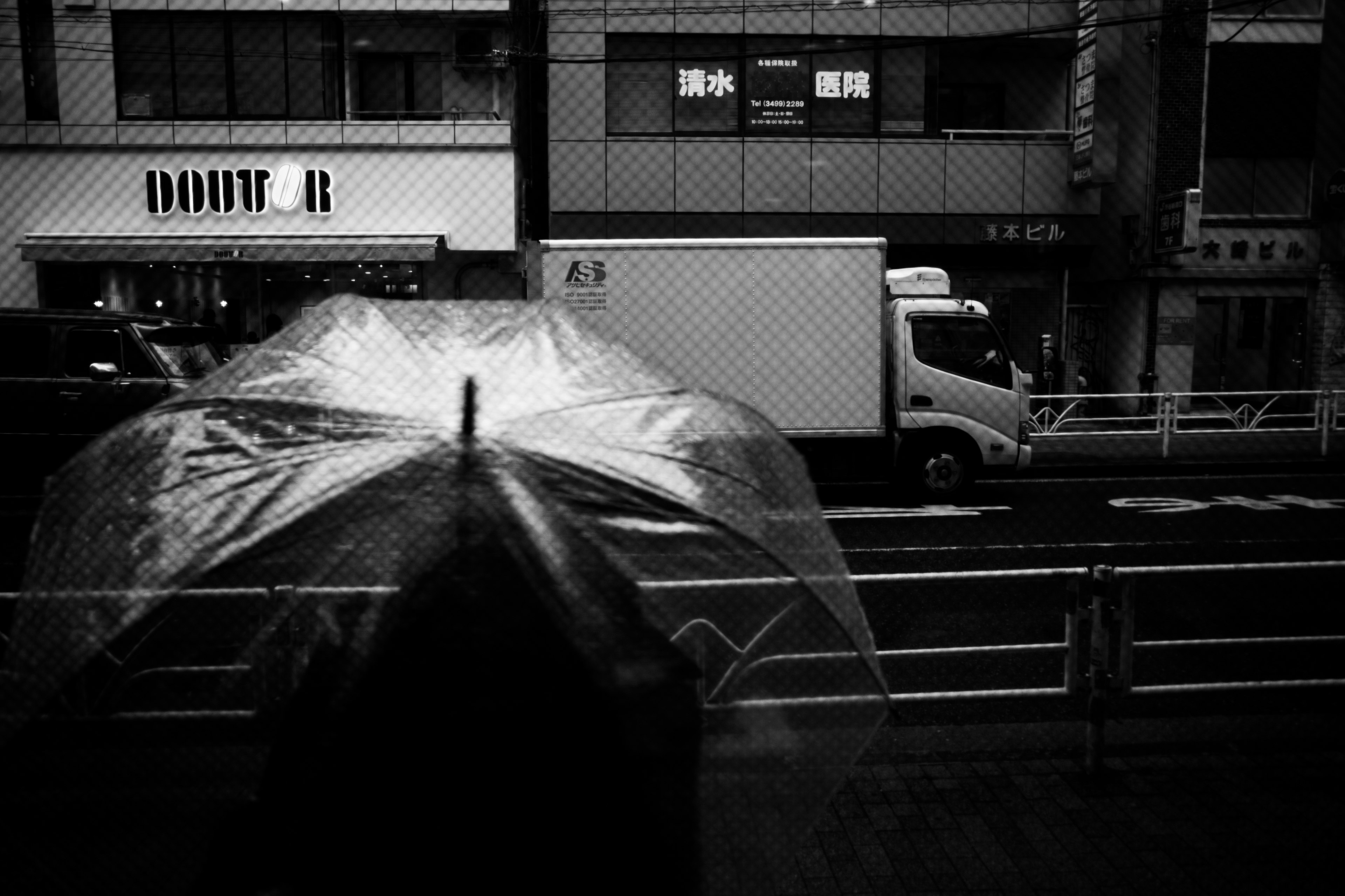 A rainy urban scene featuring a wet umbrella and monochrome buildings