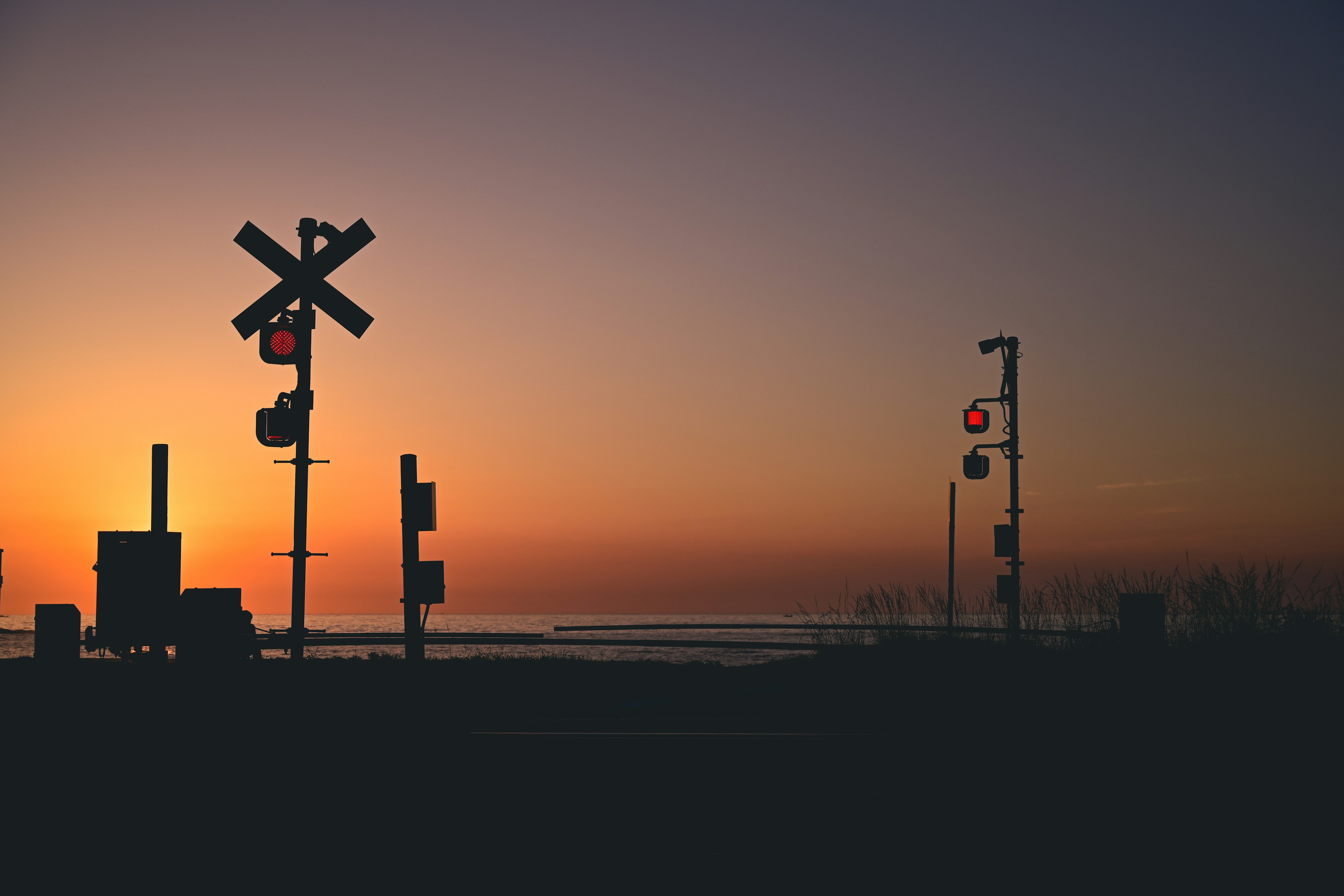 Silueta de un cruce de ferrocarril y señales al atardecer