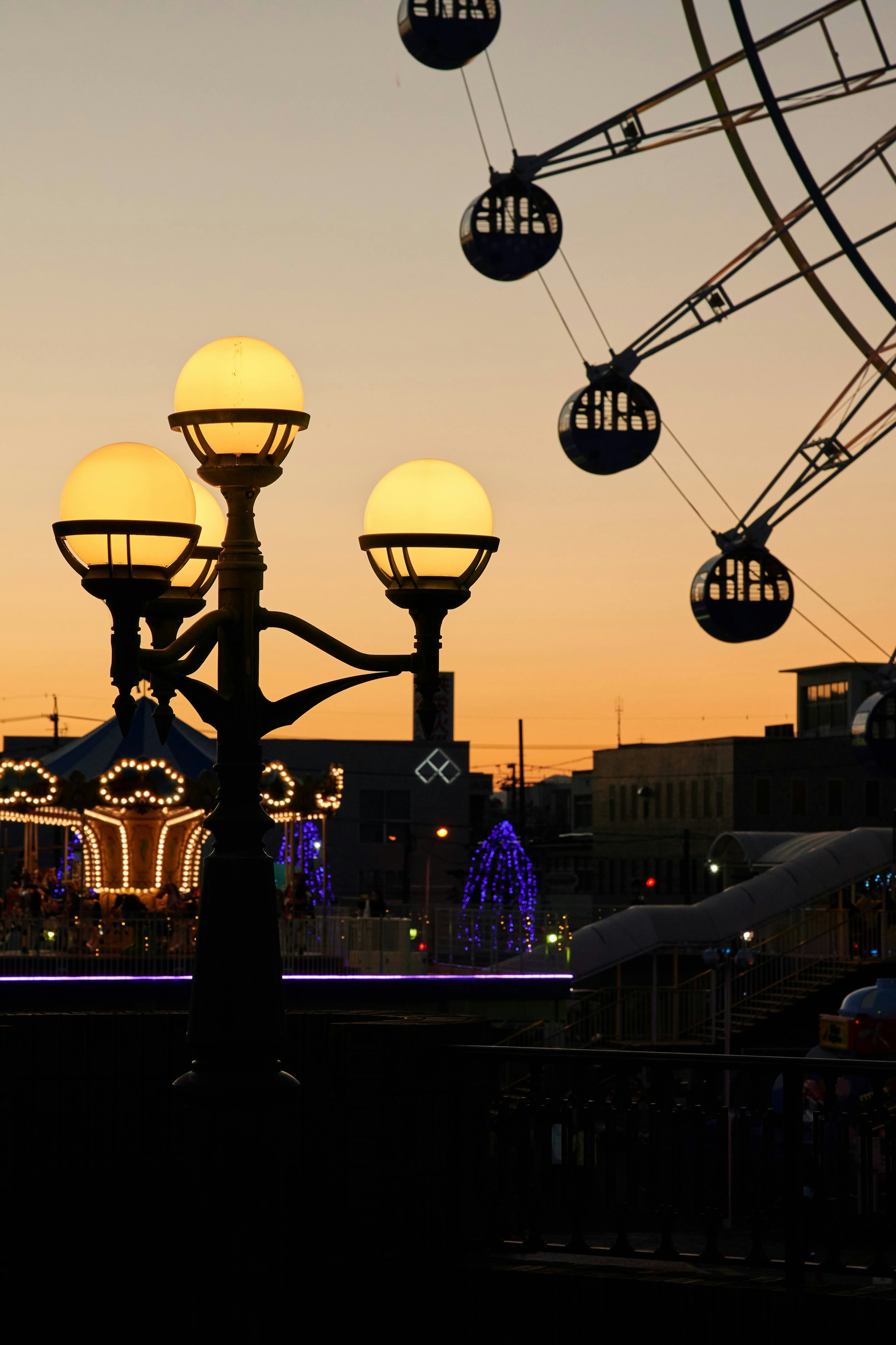 Scène de parc d'attractions avec un coucher de soleil et une grande roue