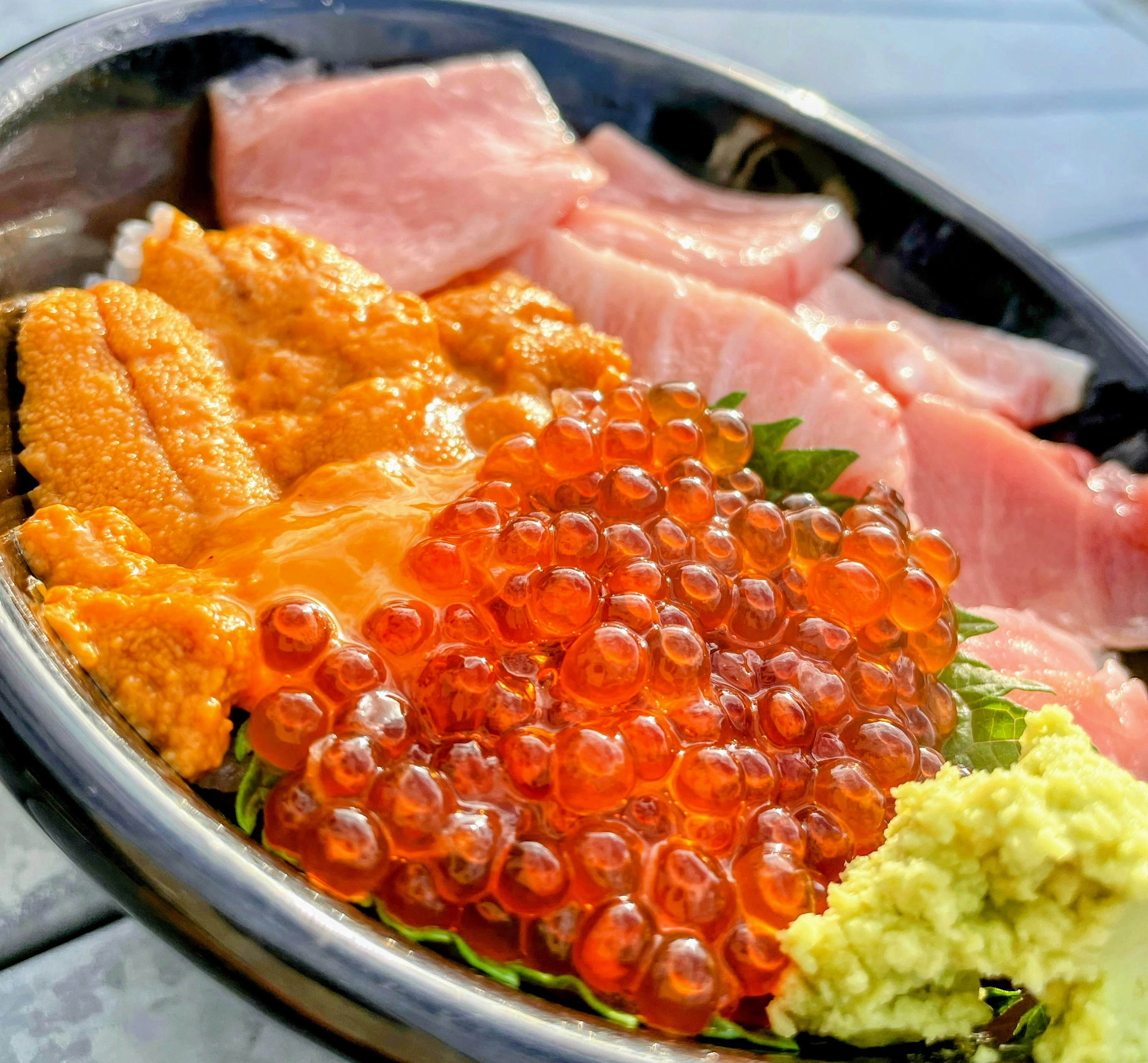 Imagen de un tazón de mariscos frescos con erizo de mar, huevas de salmón y rodajas de atún