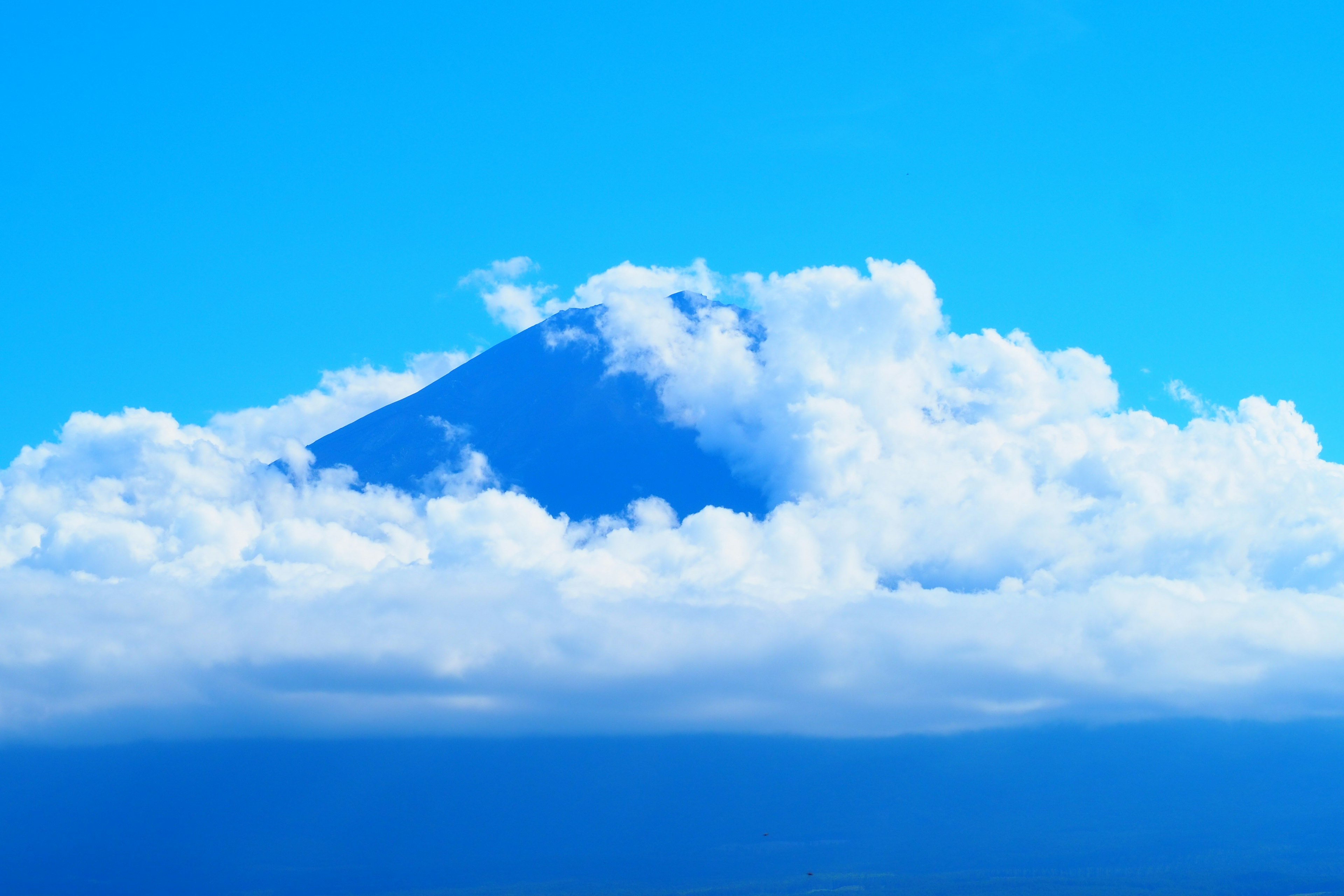 Picco di montagna circondato da nuvole sotto un cielo blu