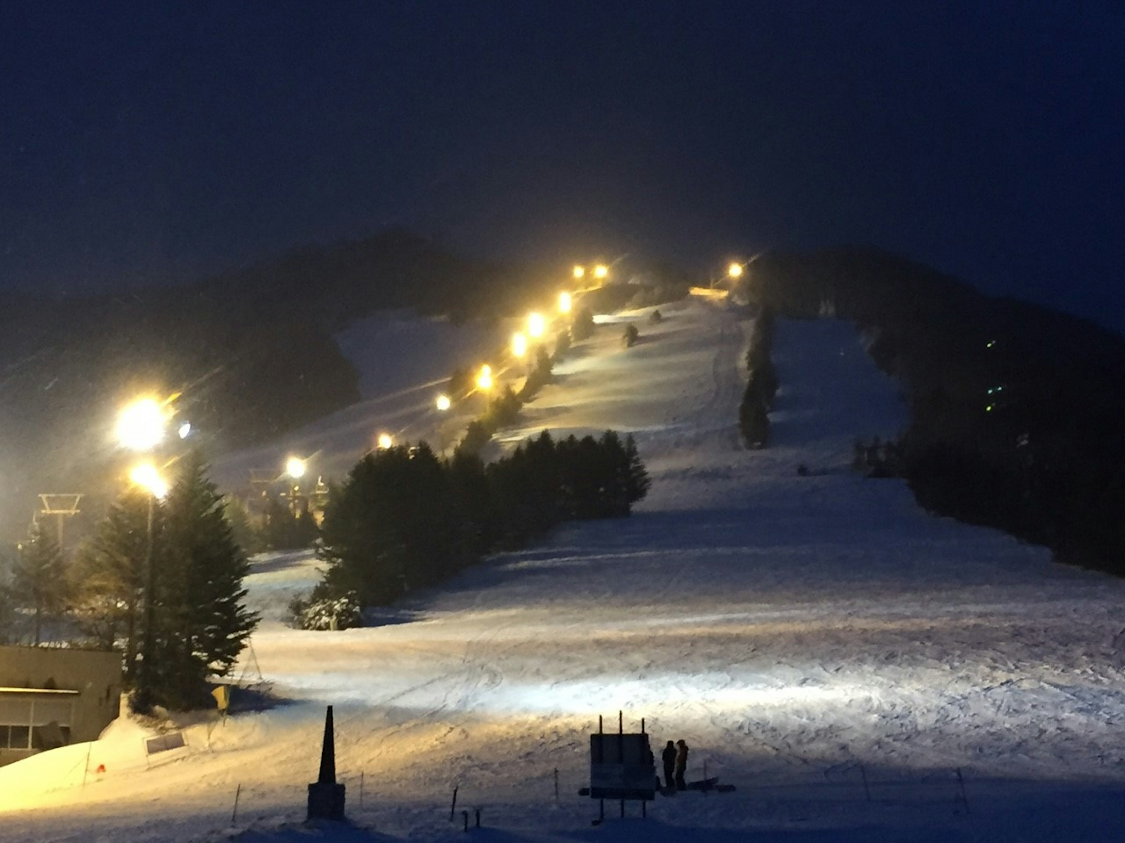 Vue nocturne d'une piste de ski enneigée avec des chemins éclairés