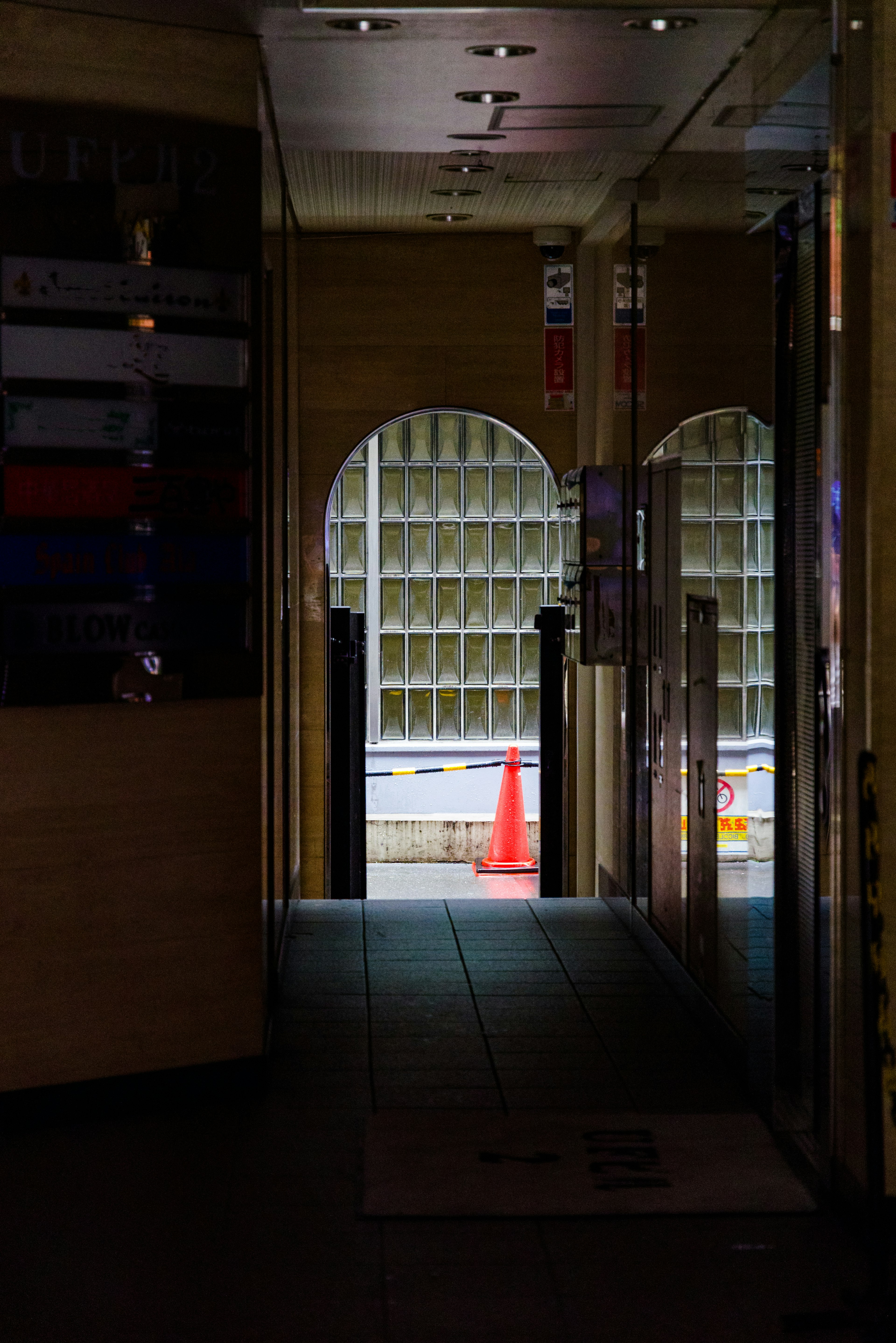 Dim hallway with an arched window revealing an orange traffic cone outside