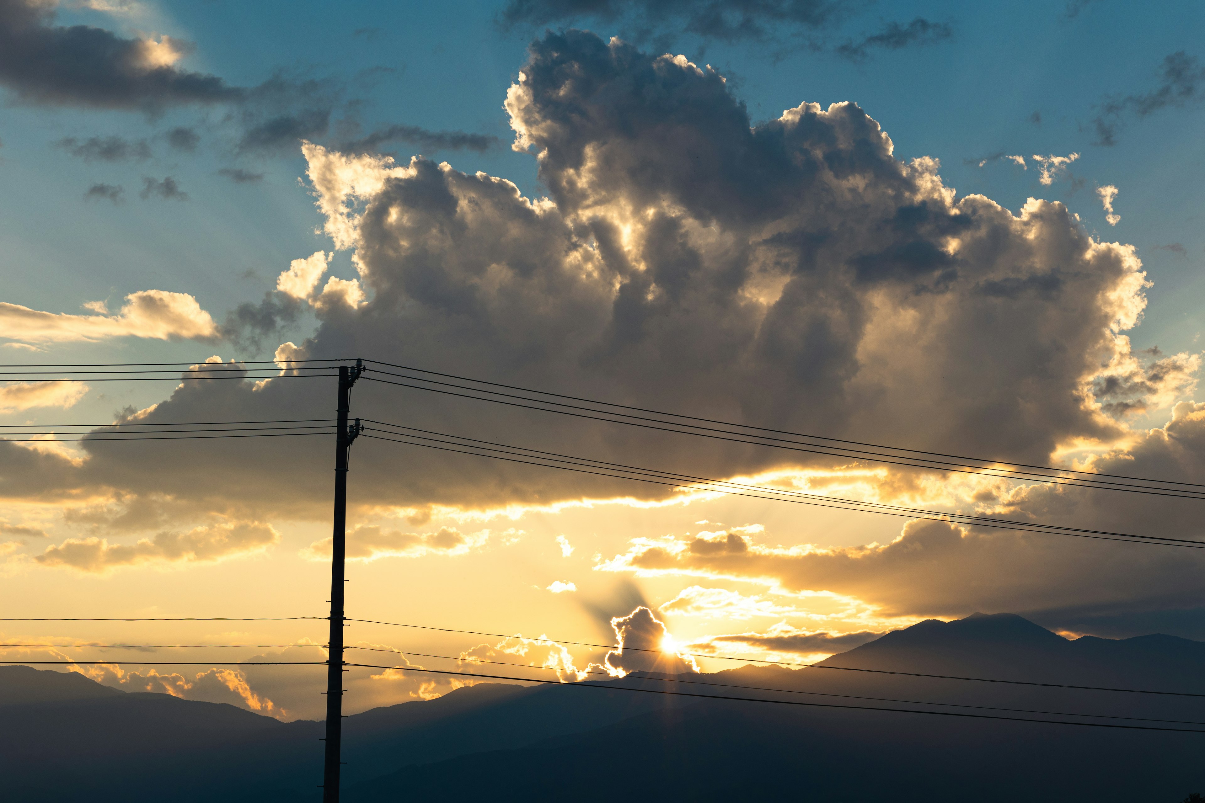 Grand nuage illuminé par le coucher de soleil avec silhouette de montagnes