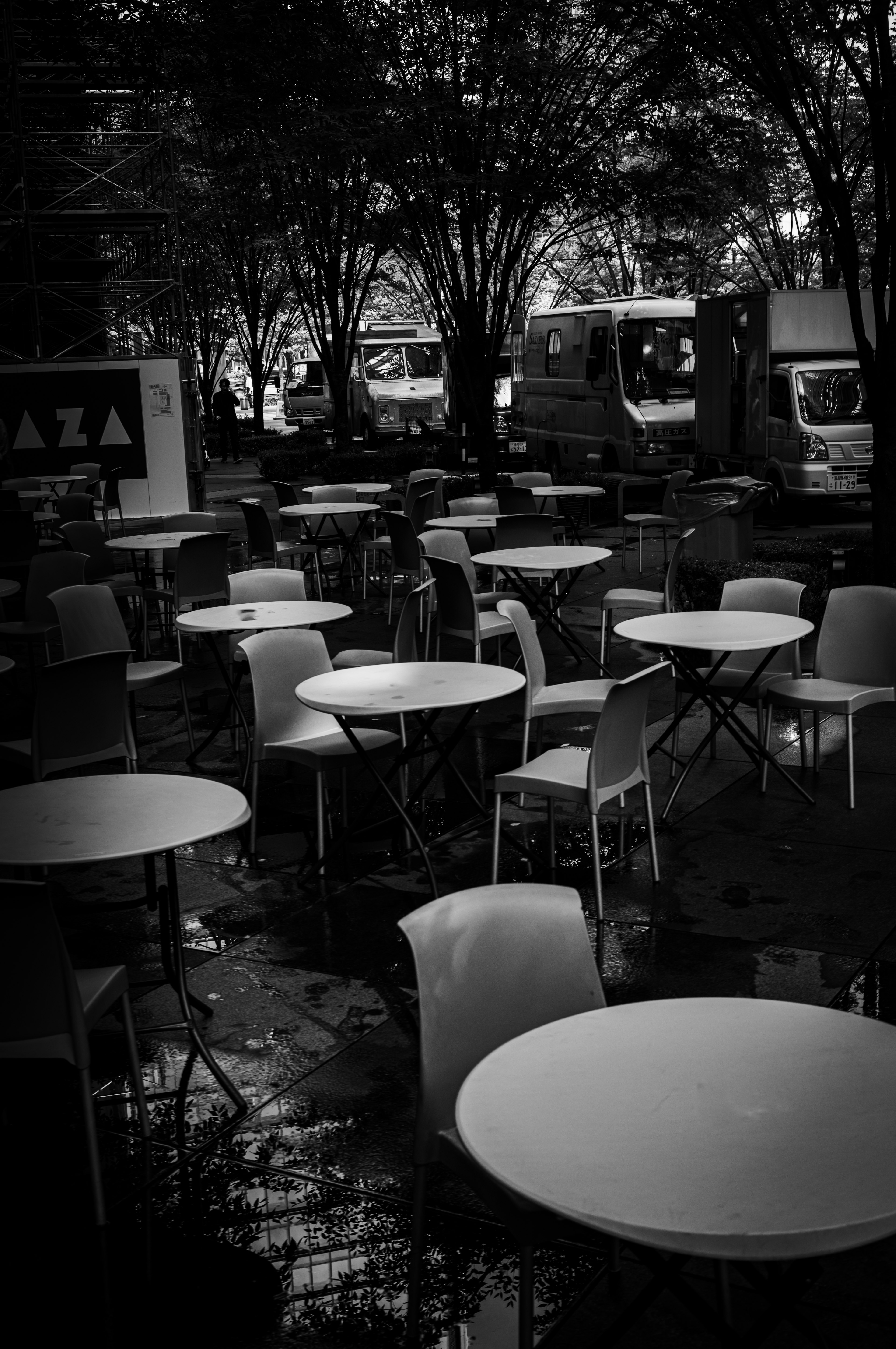 Outdoor café space with white tables arranged amidst trees