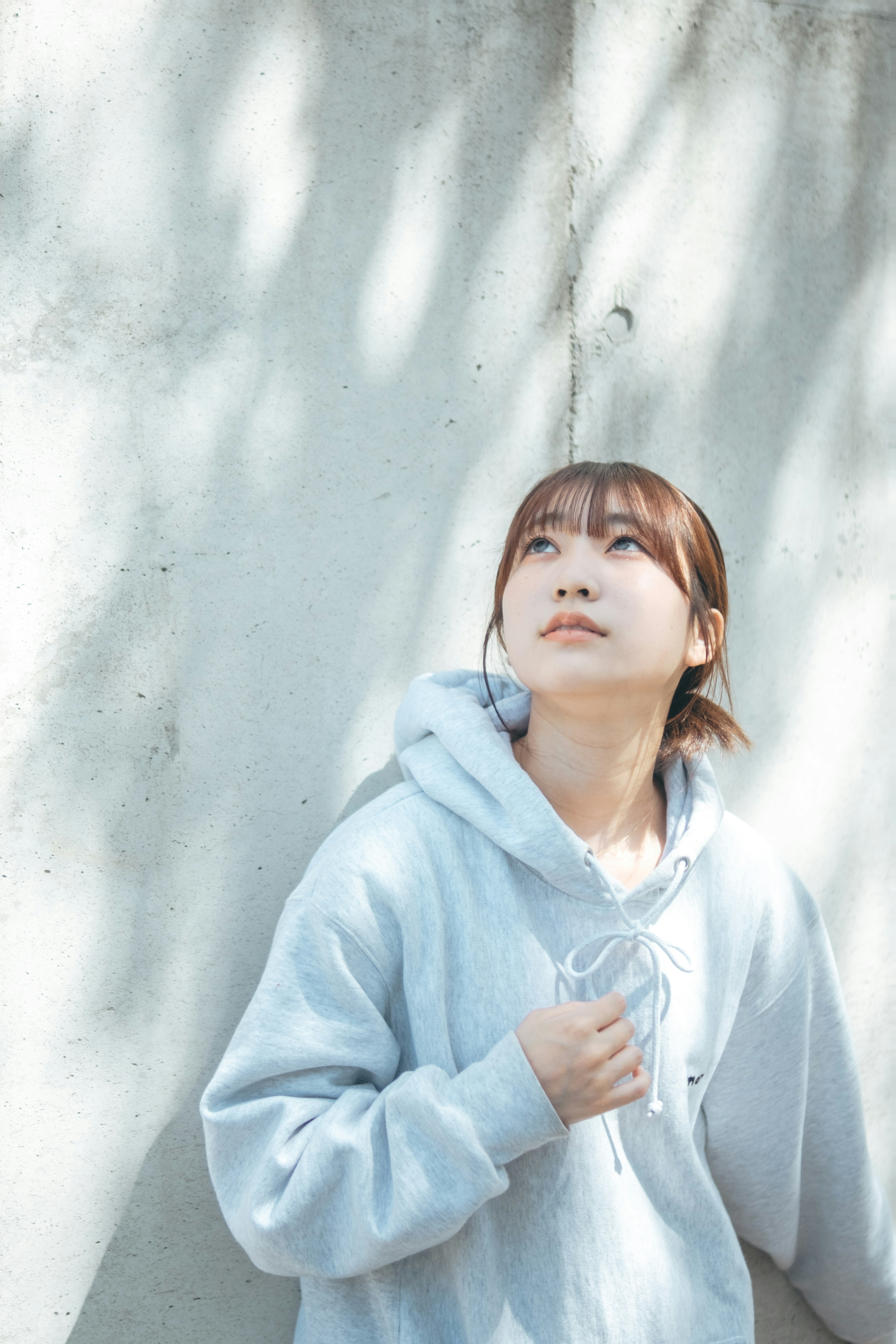 A woman in a blue hoodie looking up at a wall