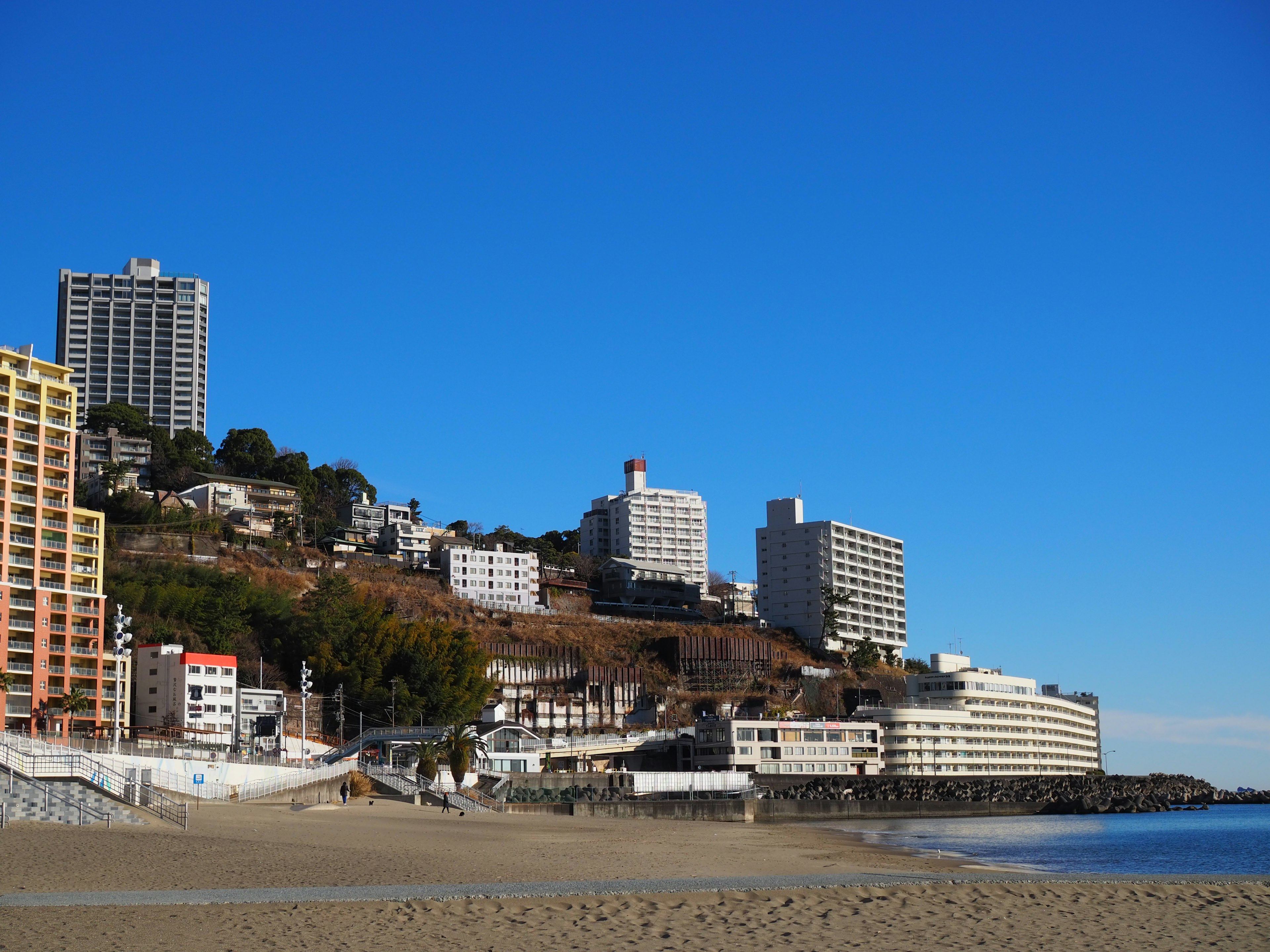 Coastal hotels along a sandy beach under a clear blue sky