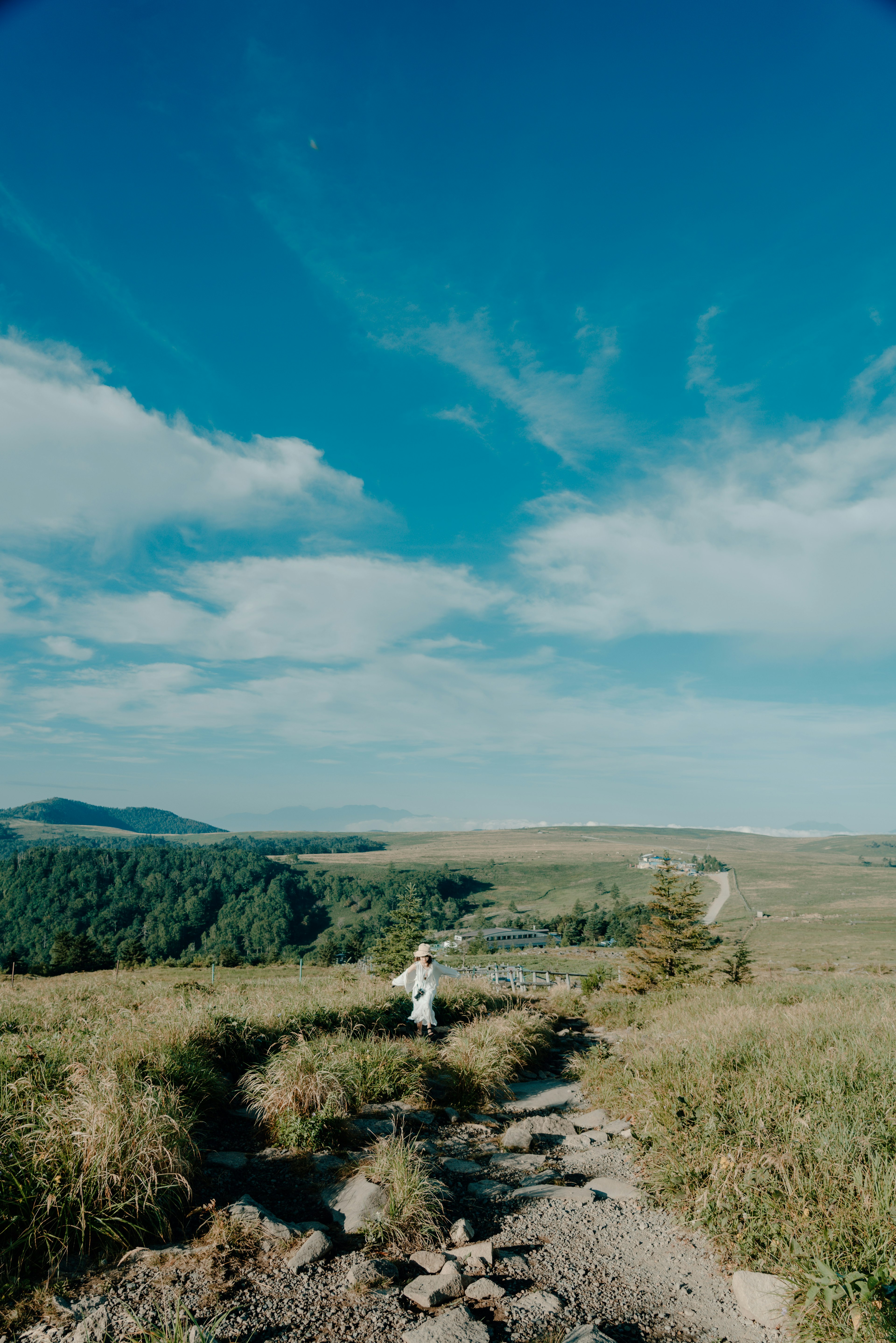 Eine Person, die auf einem Weg in einer weiten Landschaft mit blauem Himmel geht