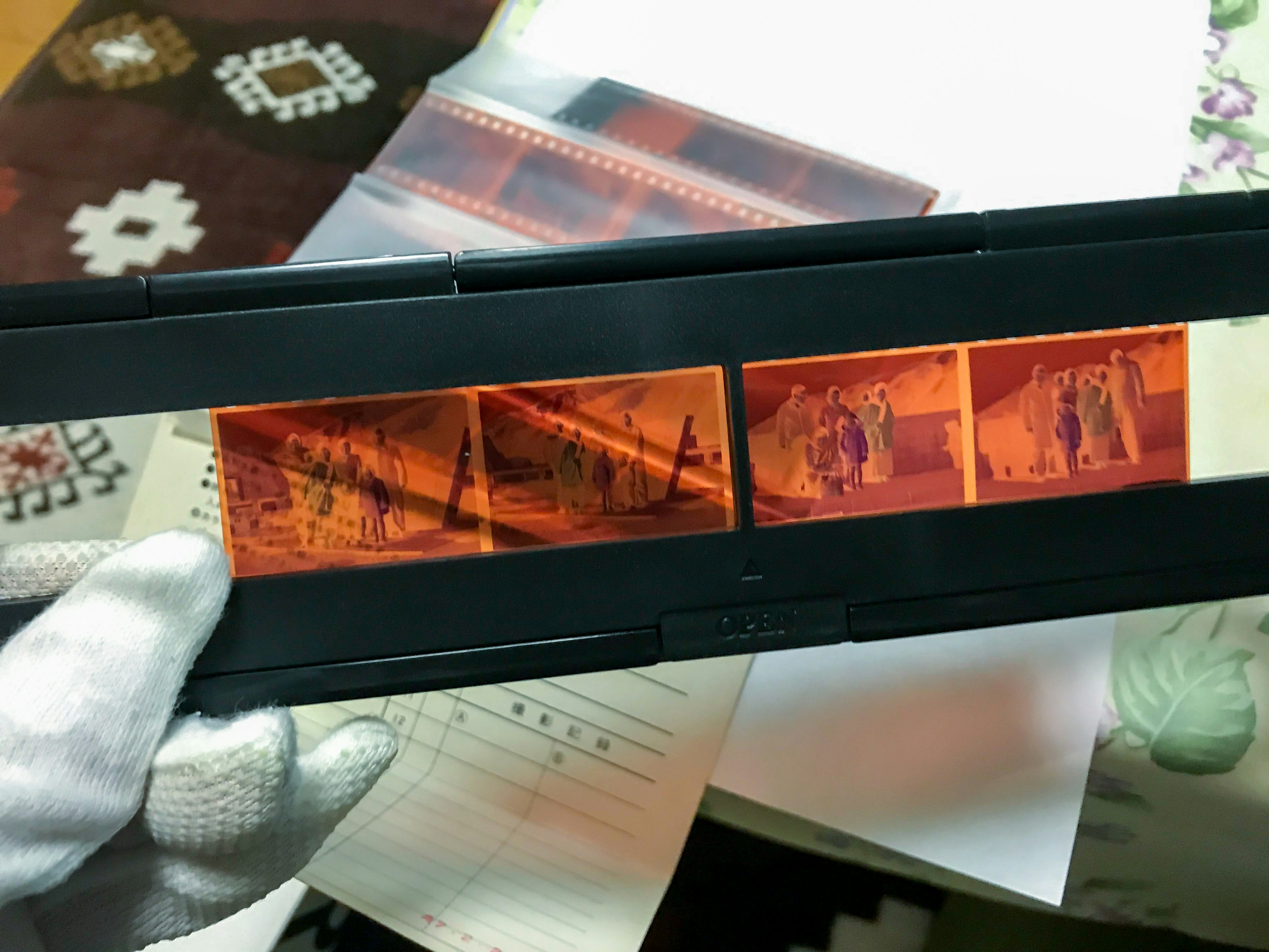 Orang yang memegang slide film dengan gambar sejarah dalam nuansa merah vintage