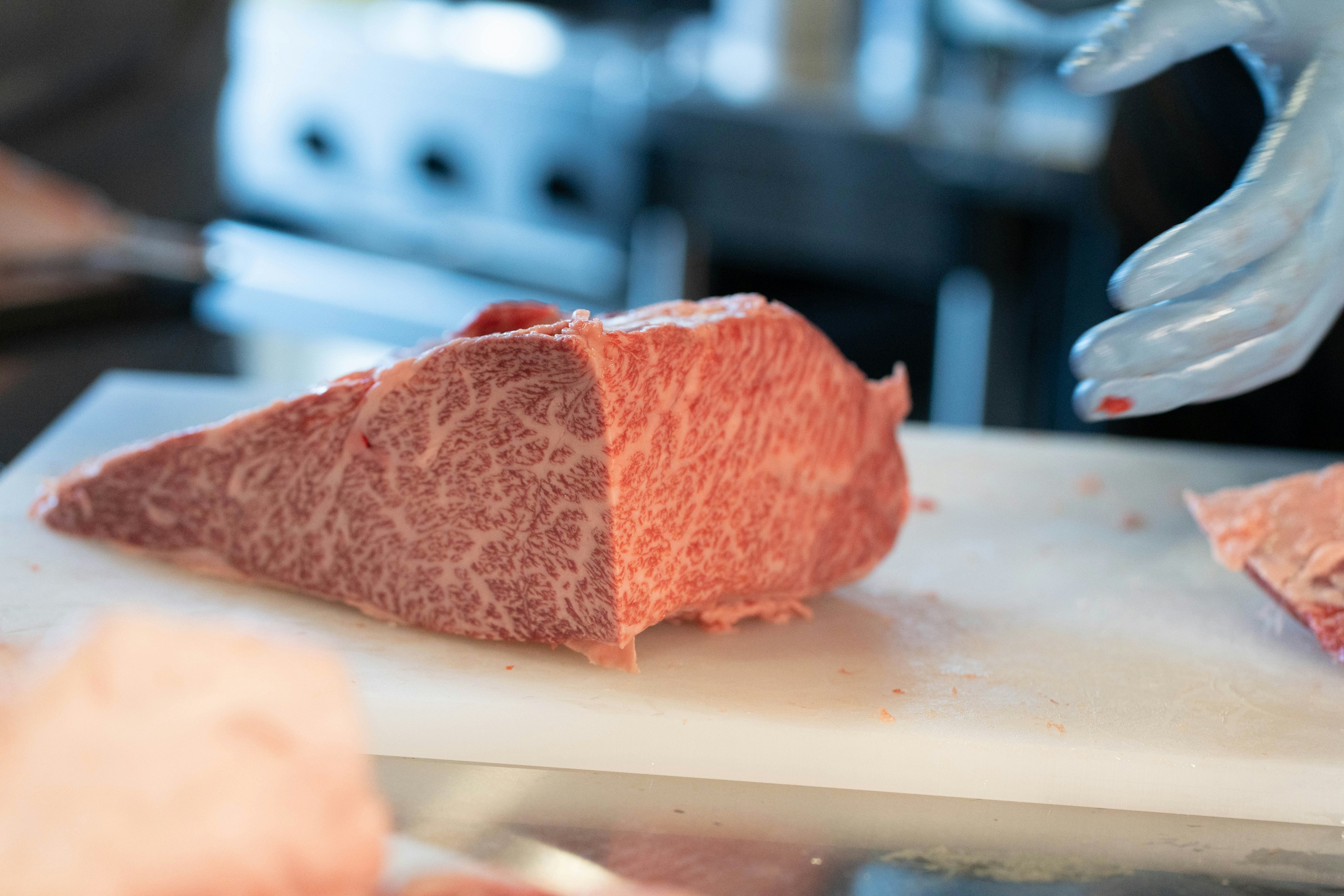 Un pezzo di carne marmorizzata in fase di taglio su un tagliere bianco