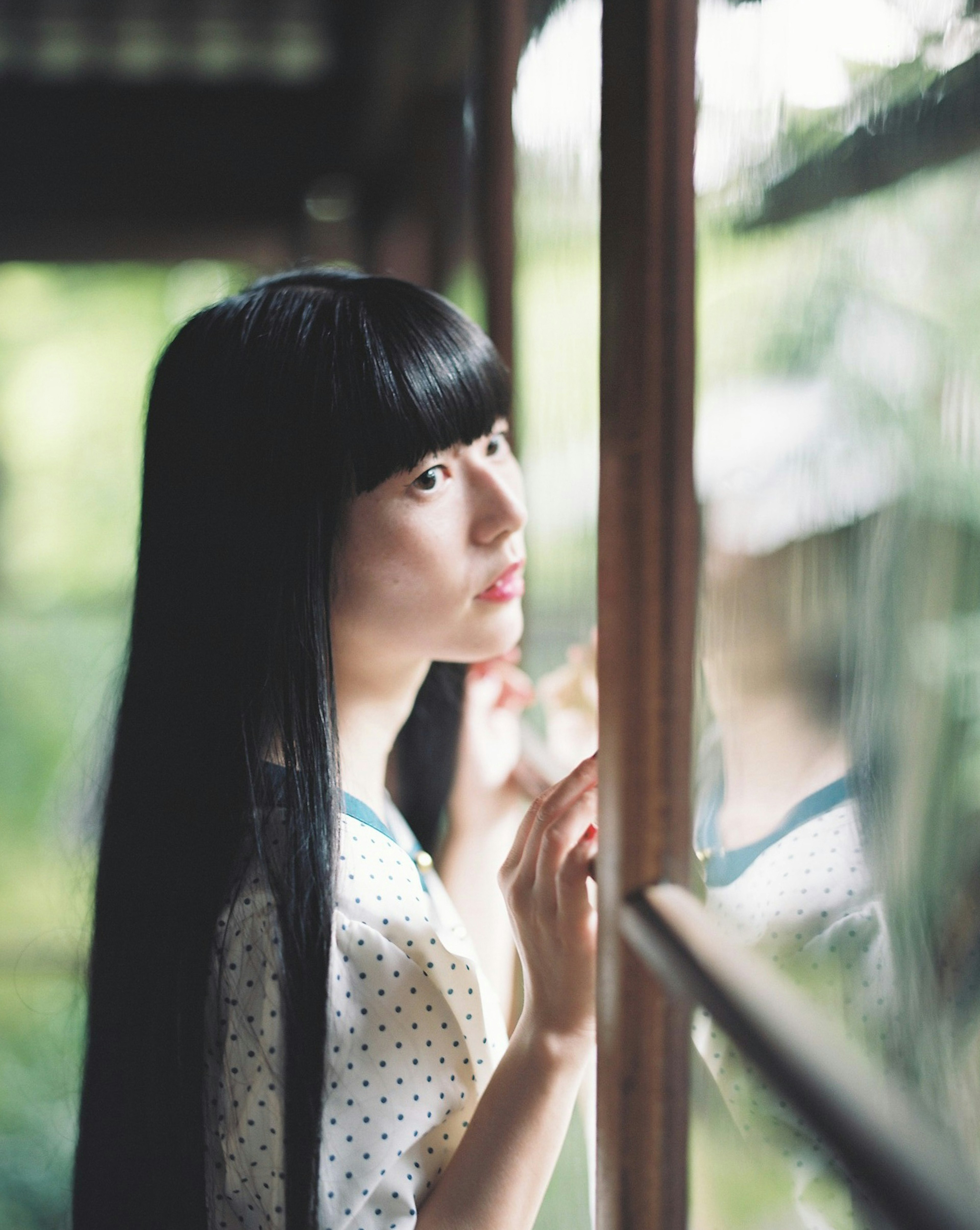 Portrait of a woman with long black hair gazing out the window