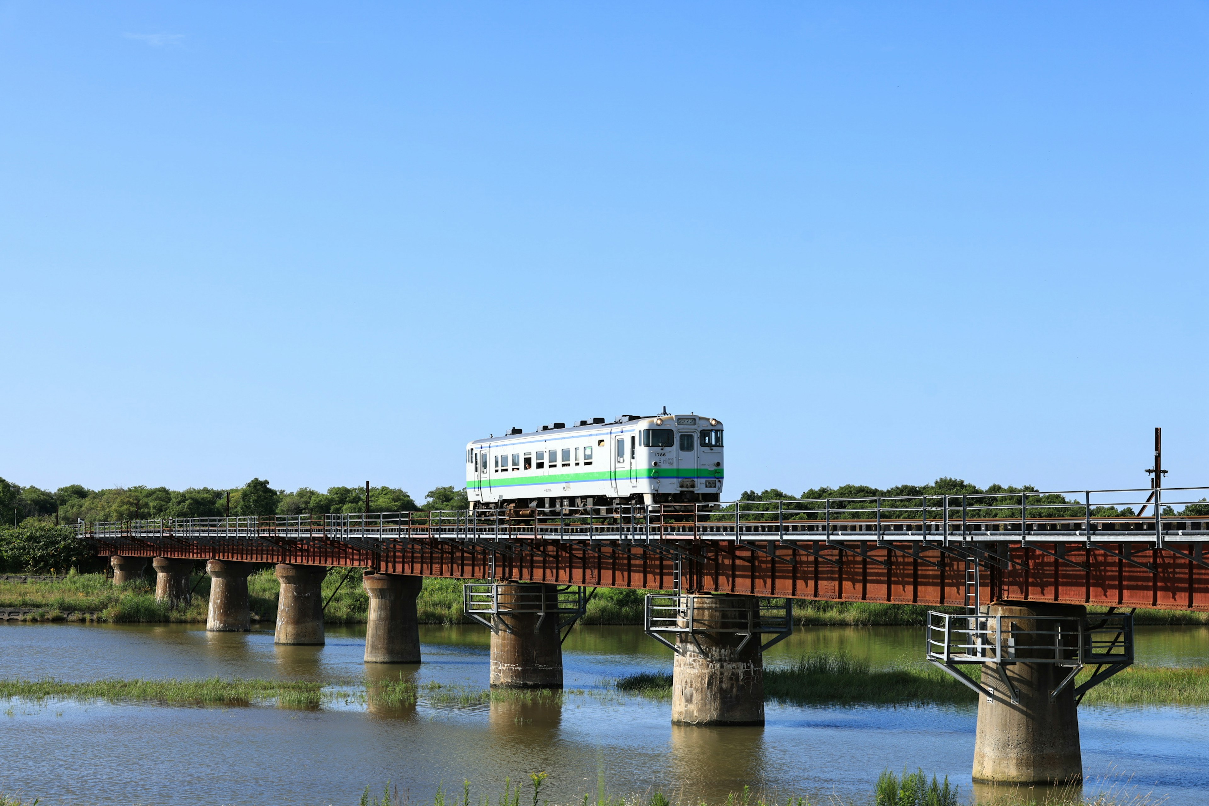 Train traversant un pont au-dessus de l'eau sous un ciel bleu clair