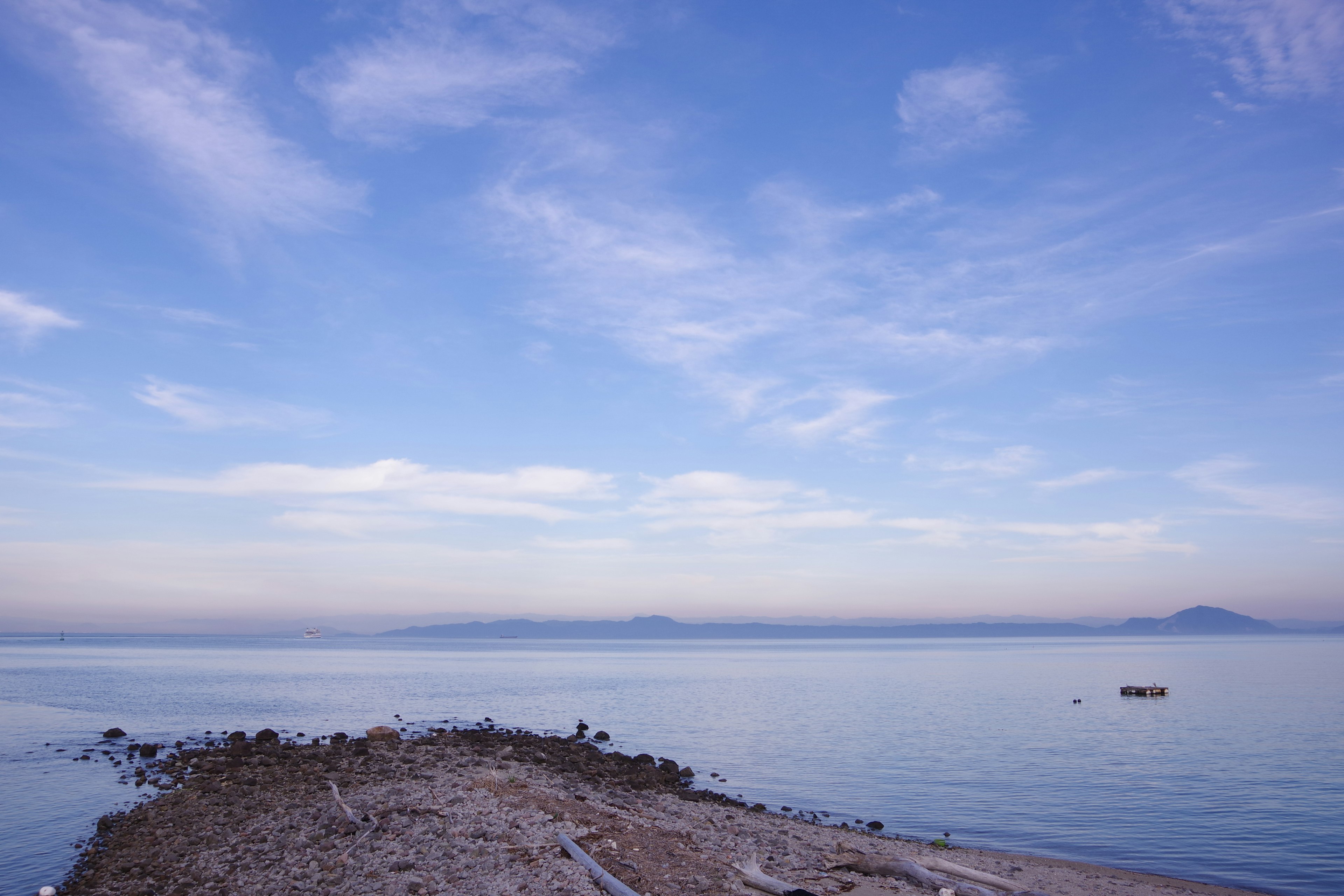 宁静海面下的蓝天风景，海岸附近有小半岛