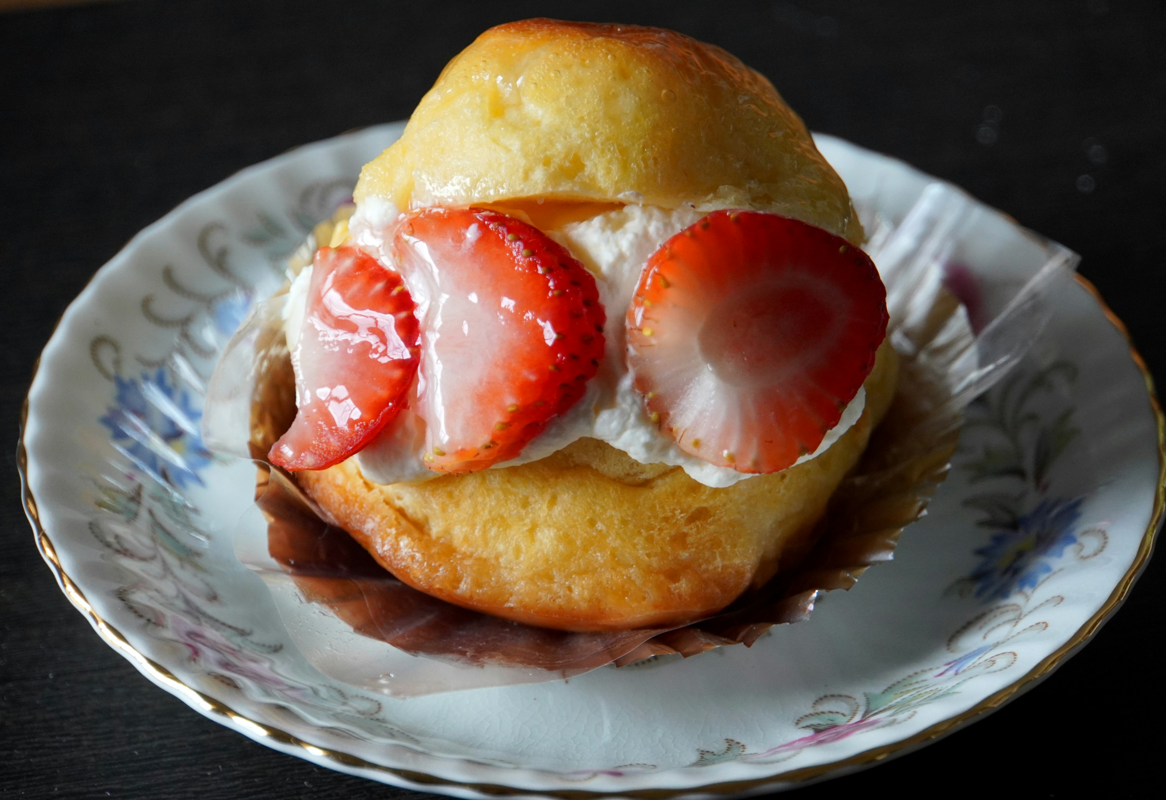 Pain sucré garni de fraises et de crème sur une assiette décorative