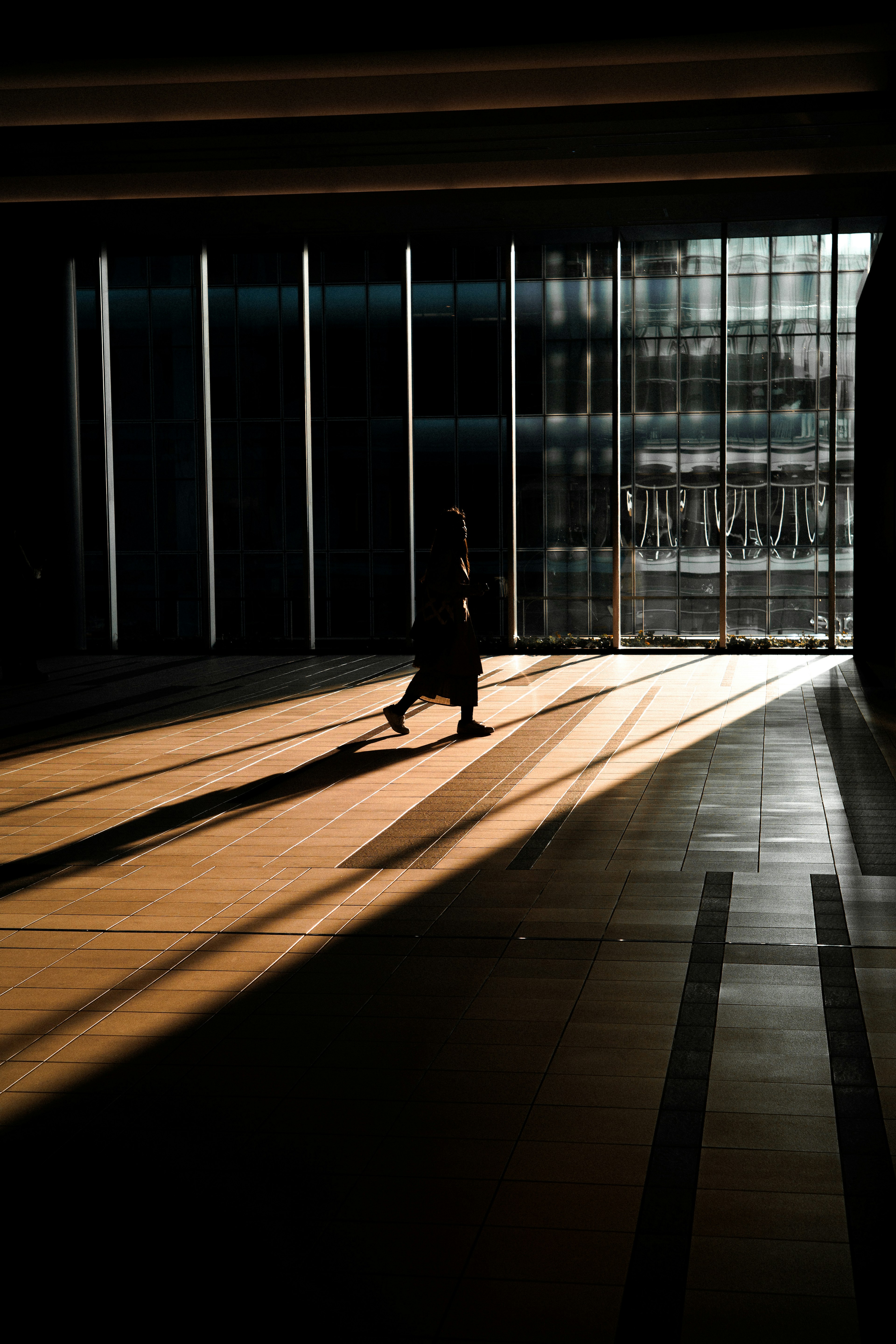 Una persona che cammina all'interno di un edificio con forti contrasti di luce e ombra