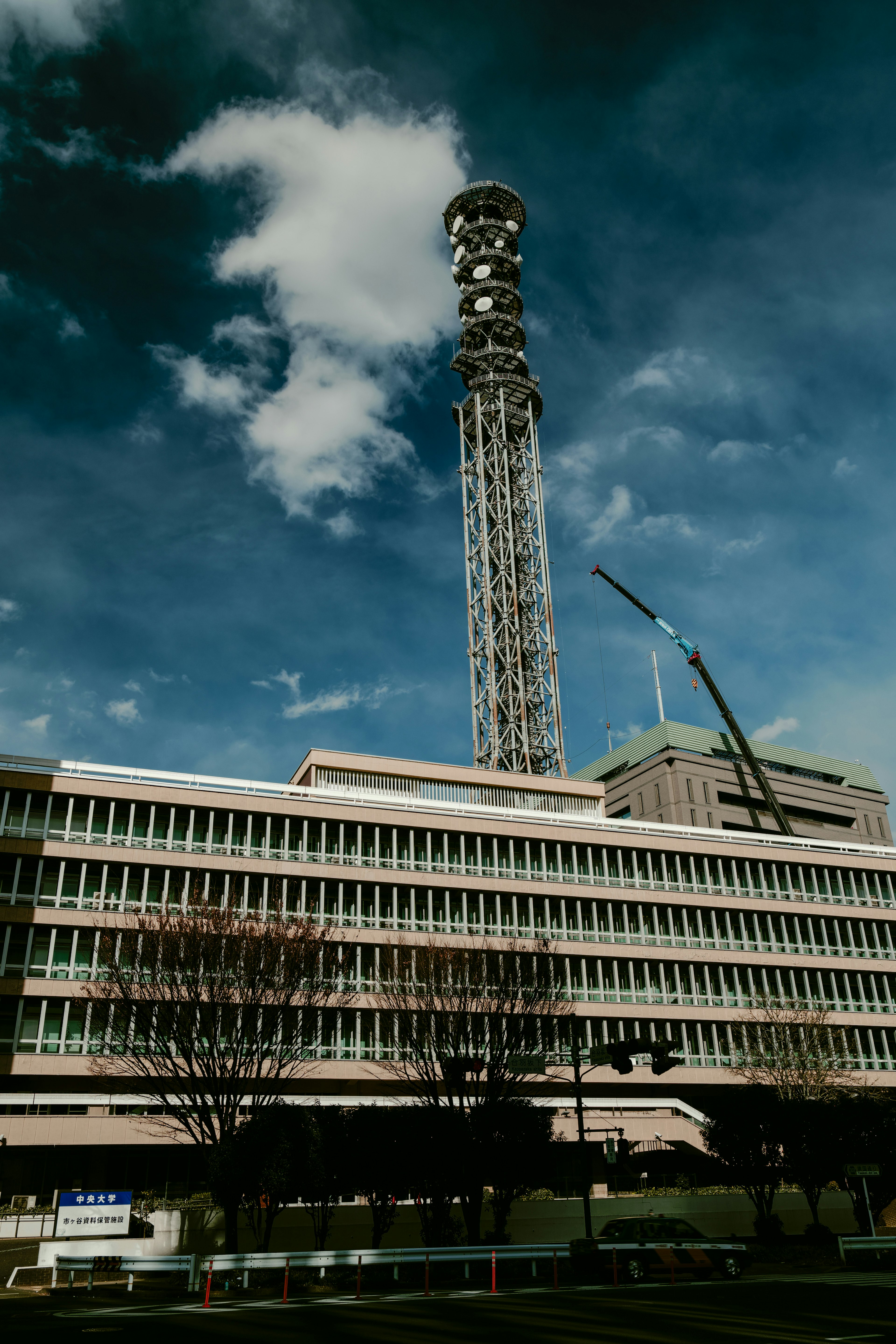 Hoher Kommunikationsturm neben einem Gebäude unter einem blauen Himmel