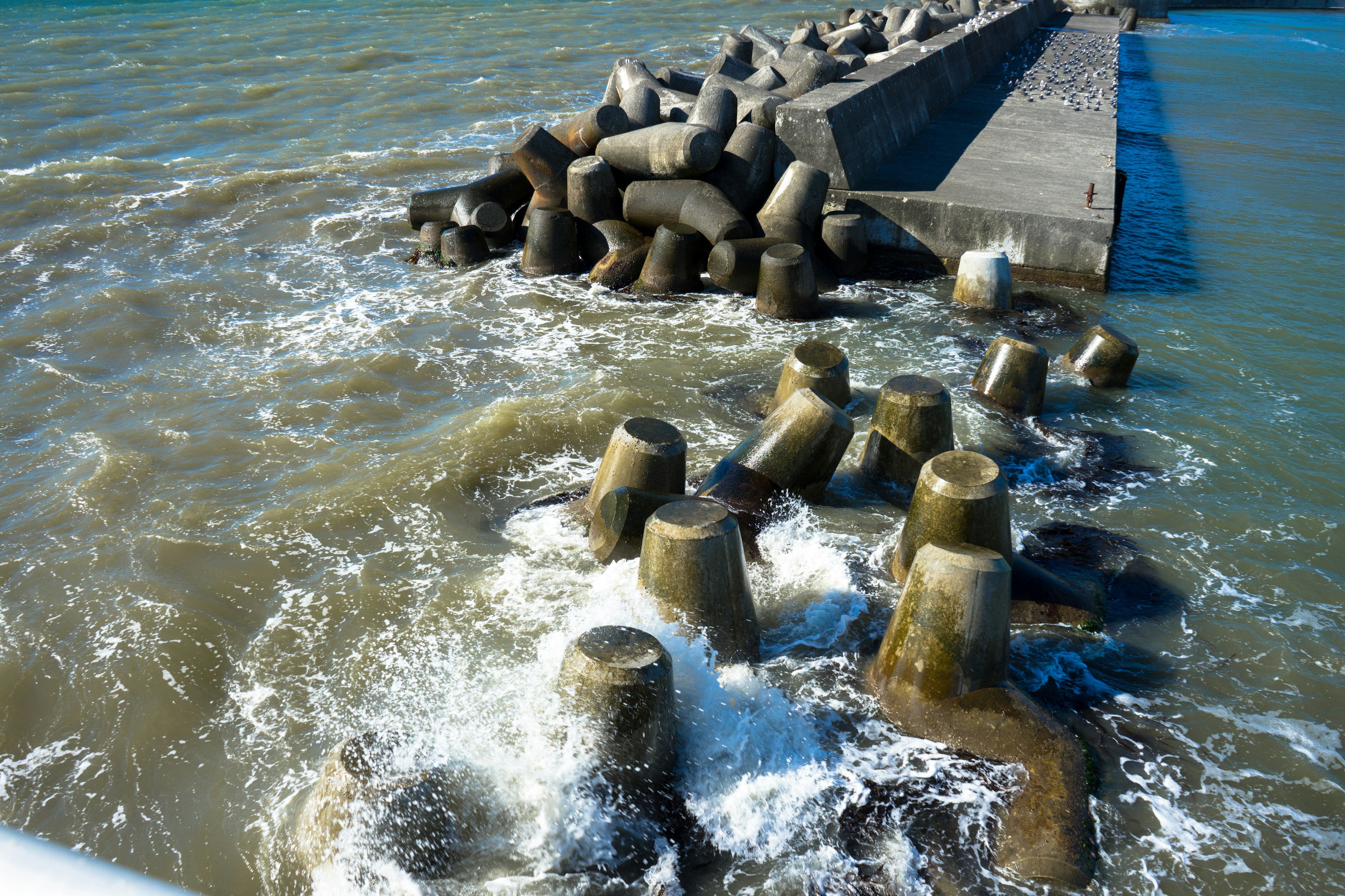 Concrete breakwater with tetrapods being washed by waves