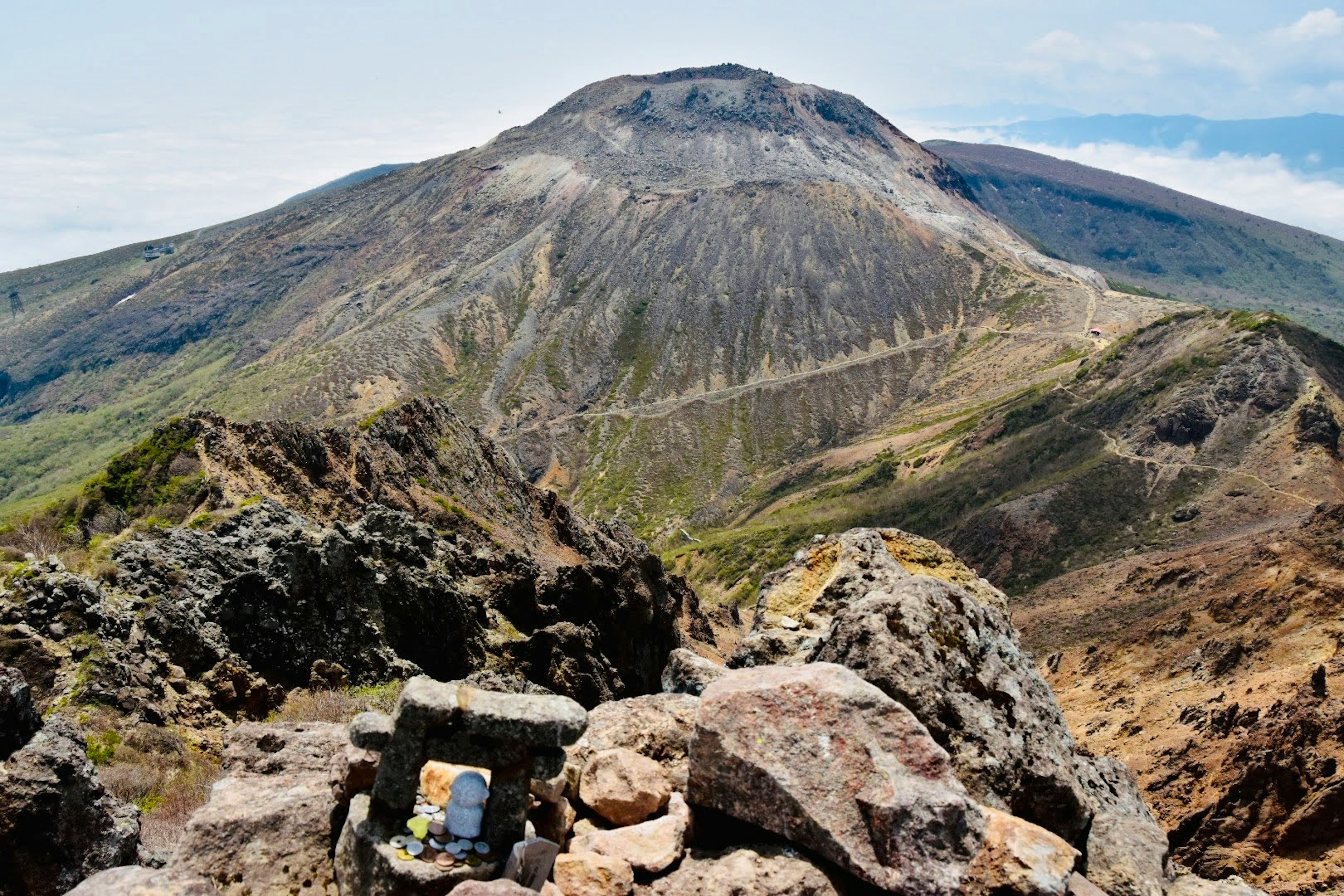 Vista desde la cumbre de un volcán con terreno rocoso y vegetación exuberante