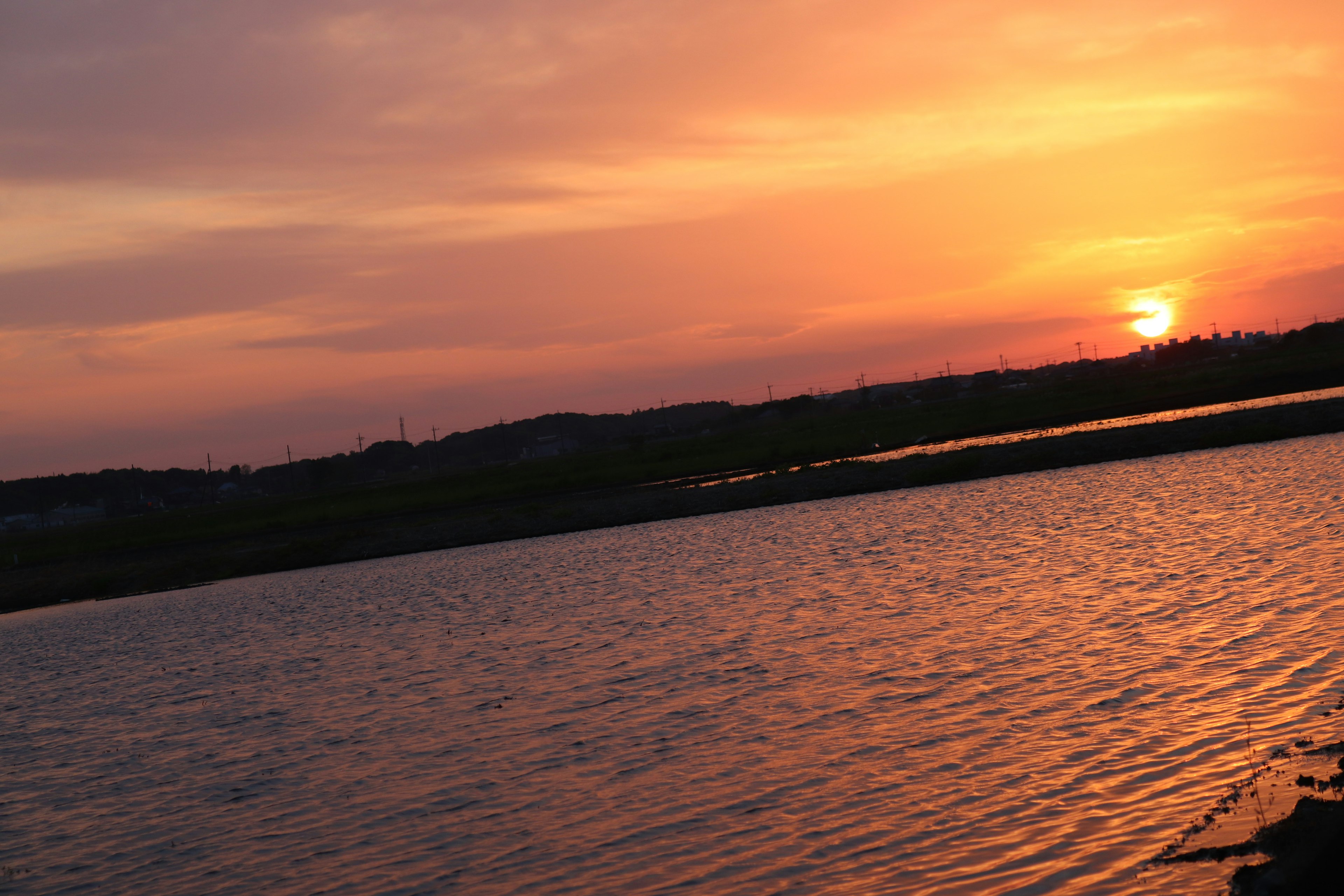 美しい夕焼けの風景で水面がオレンジ色に照らされている