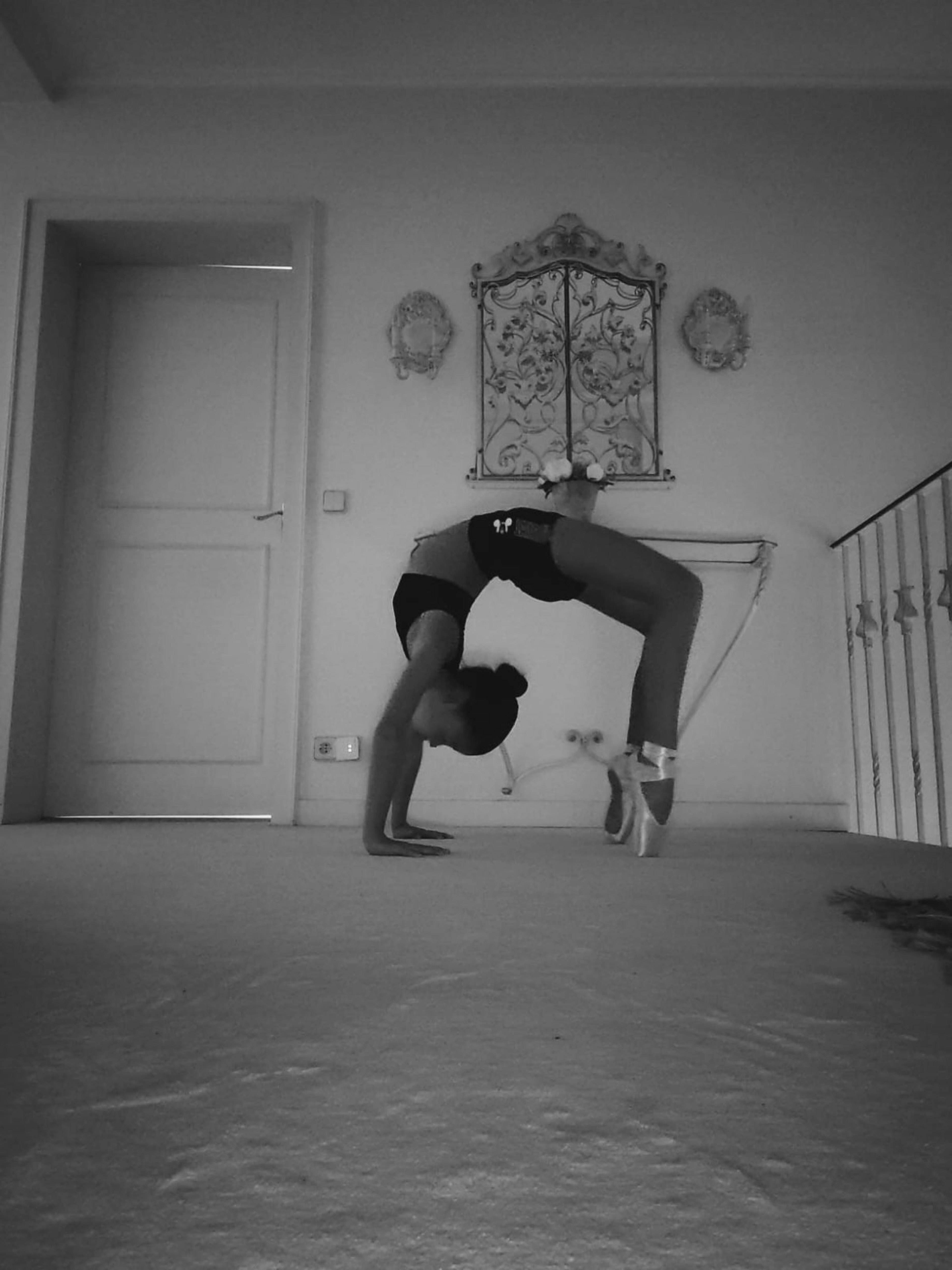 A woman performing a backbend pose in a monochrome setting