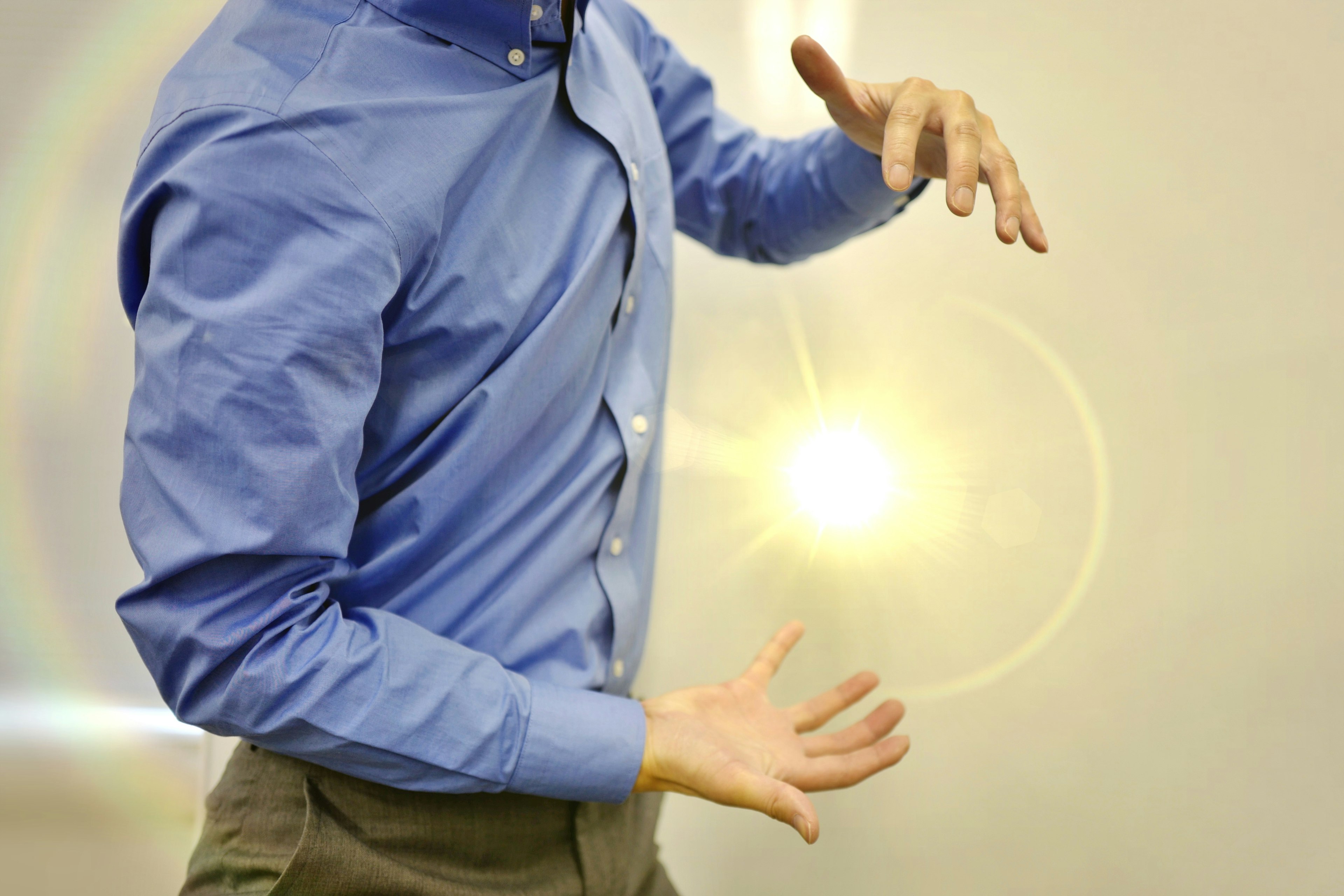 Un hombre con camisa azul gesticulando con las manos para mostrar un orbe brillante