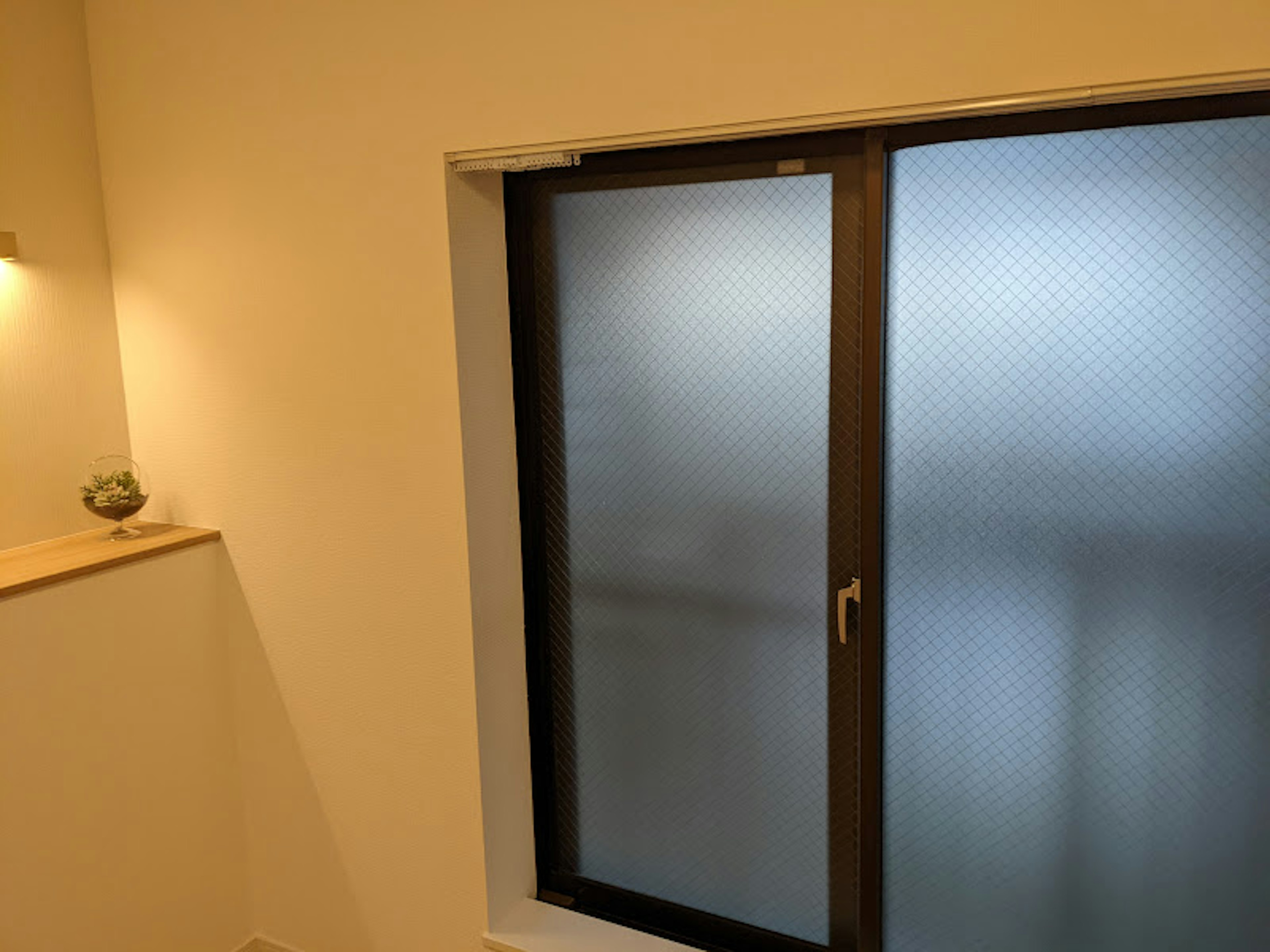 Room with white walls featuring a frosted window and wooden shelf