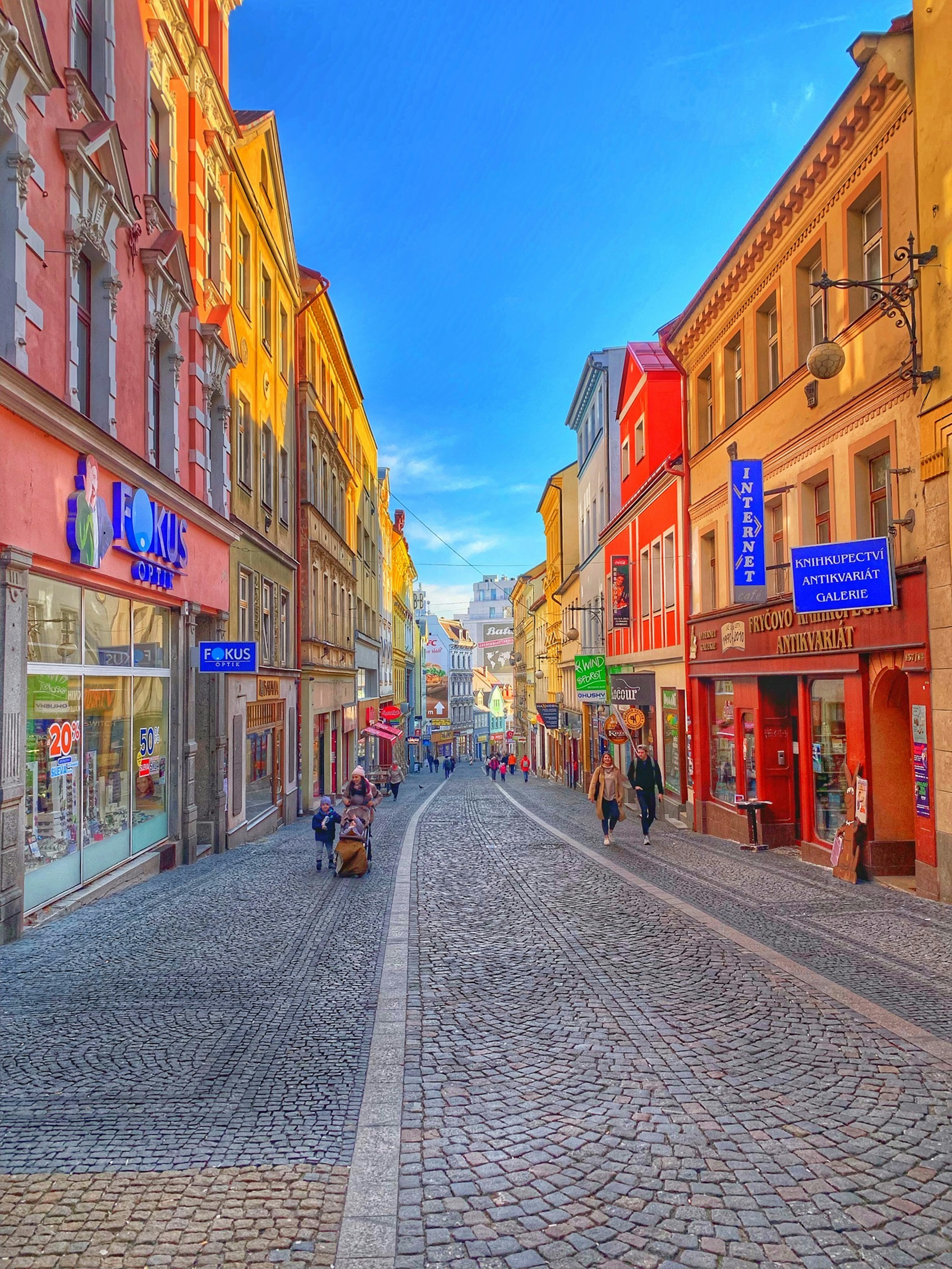 Eine gepflasterte Straße mit bunten Gebäuden und gehenden Menschen