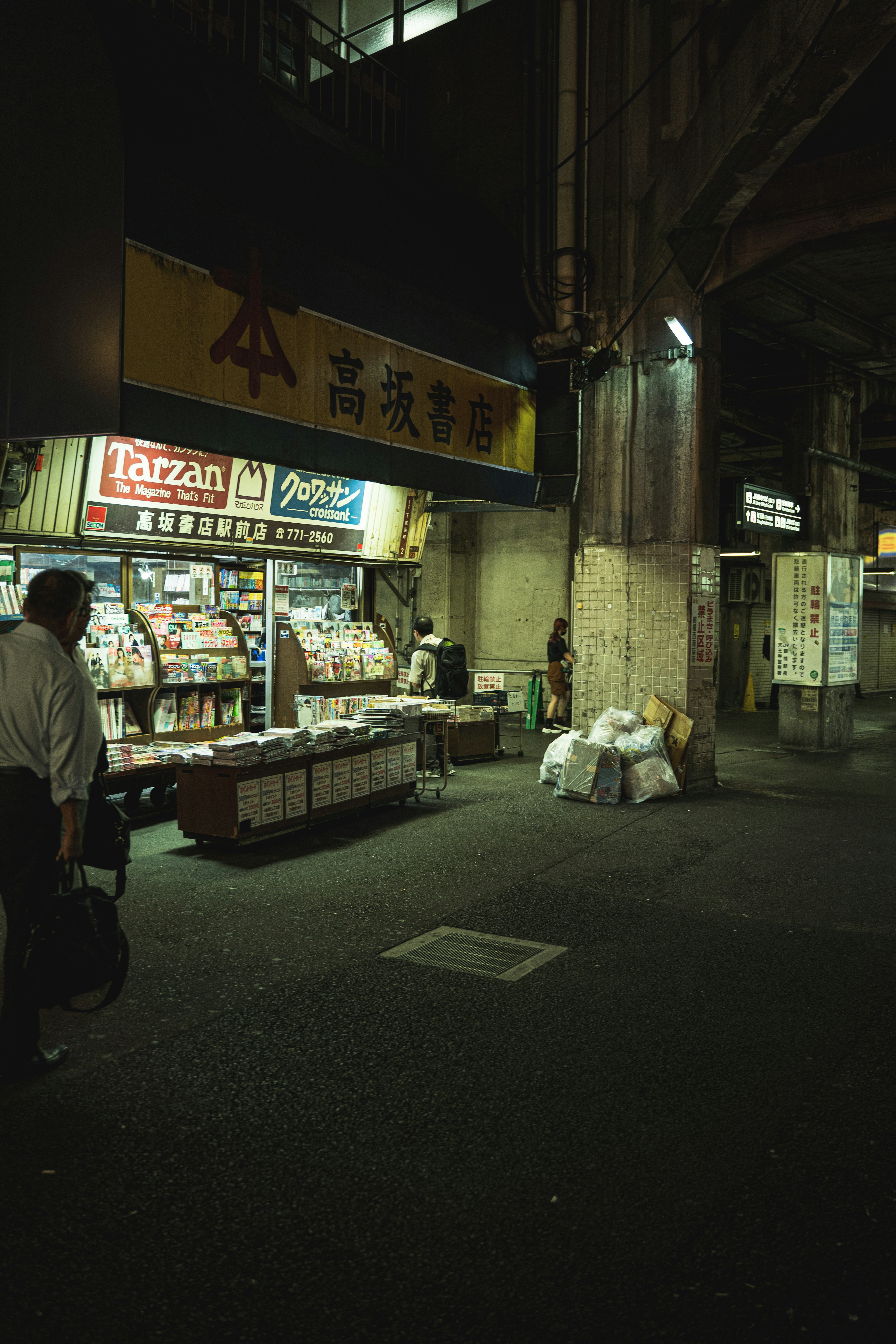 ถนนที่มีแสงน้อยมีร้านหนังสือเก่าและกองขยะ