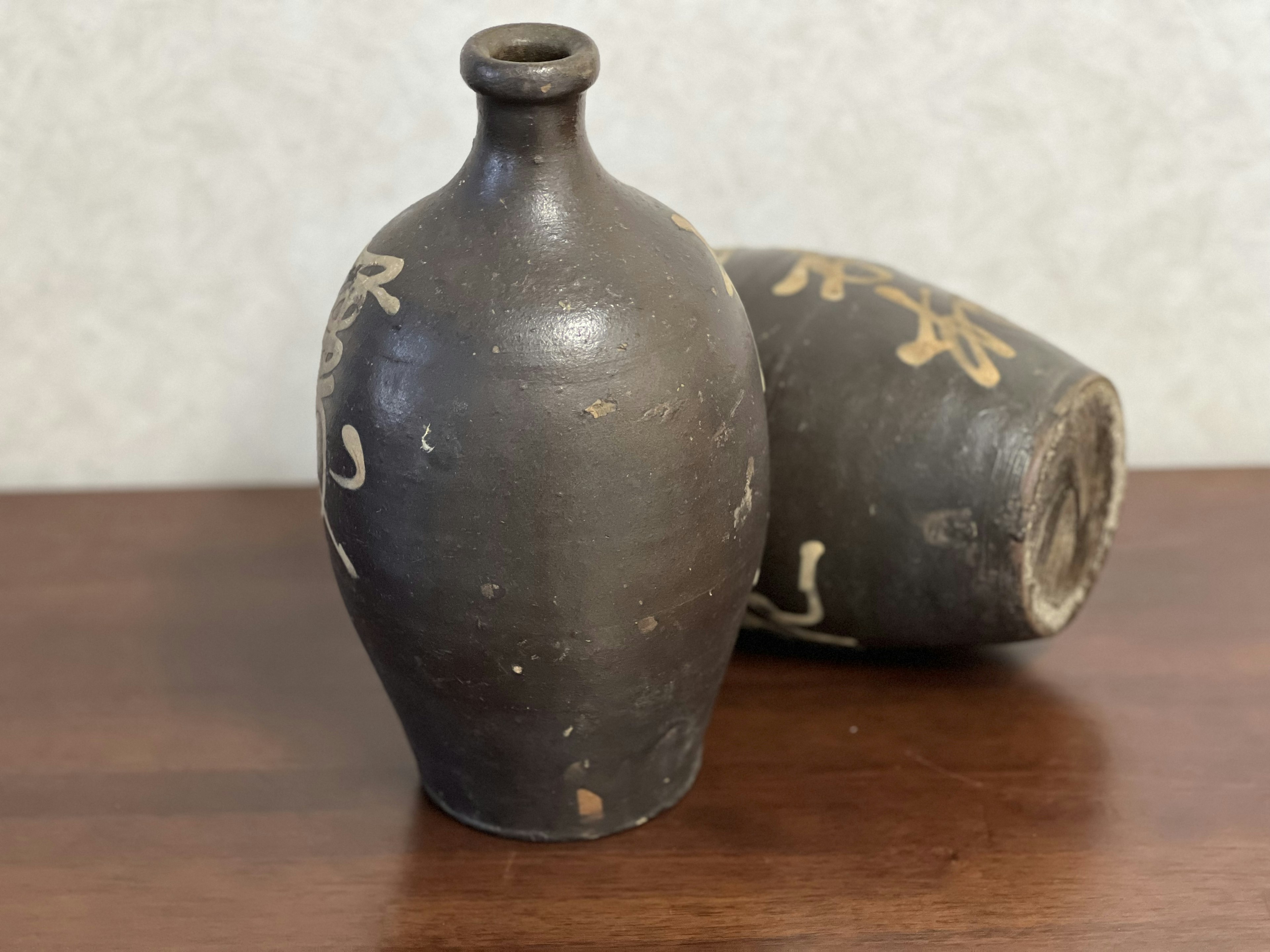 Black ceramic vase and pottery piece on a wooden surface