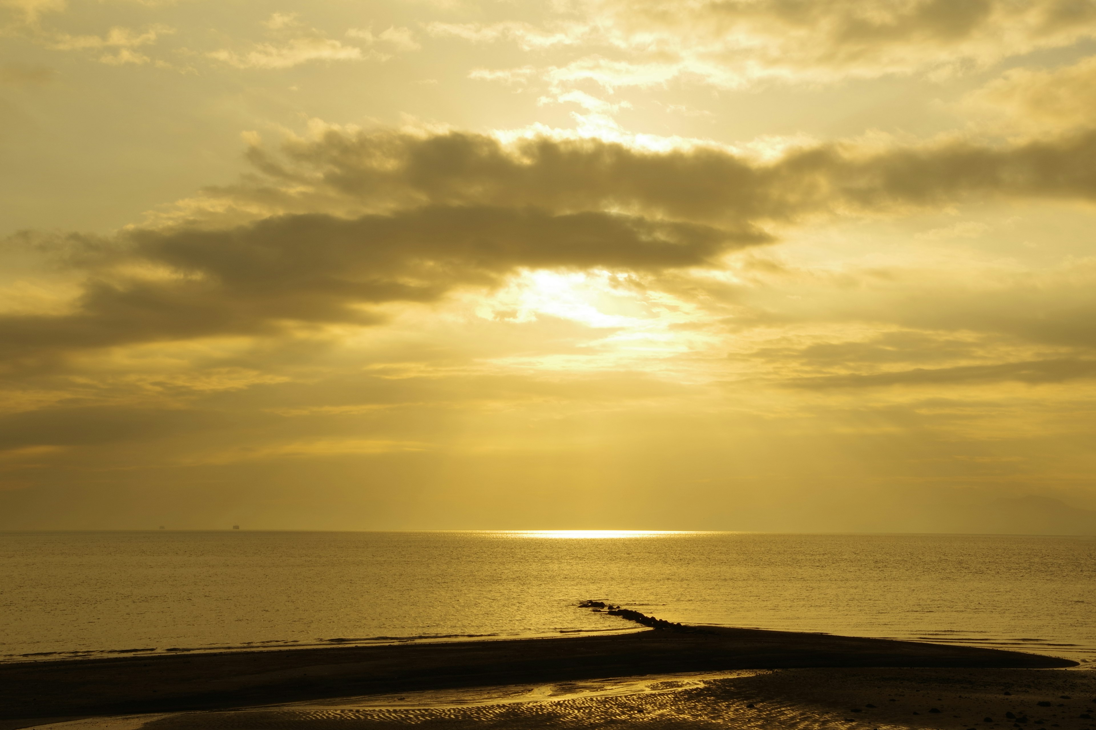 Puesta de sol dorada sobre el océano con la silueta de un muelle