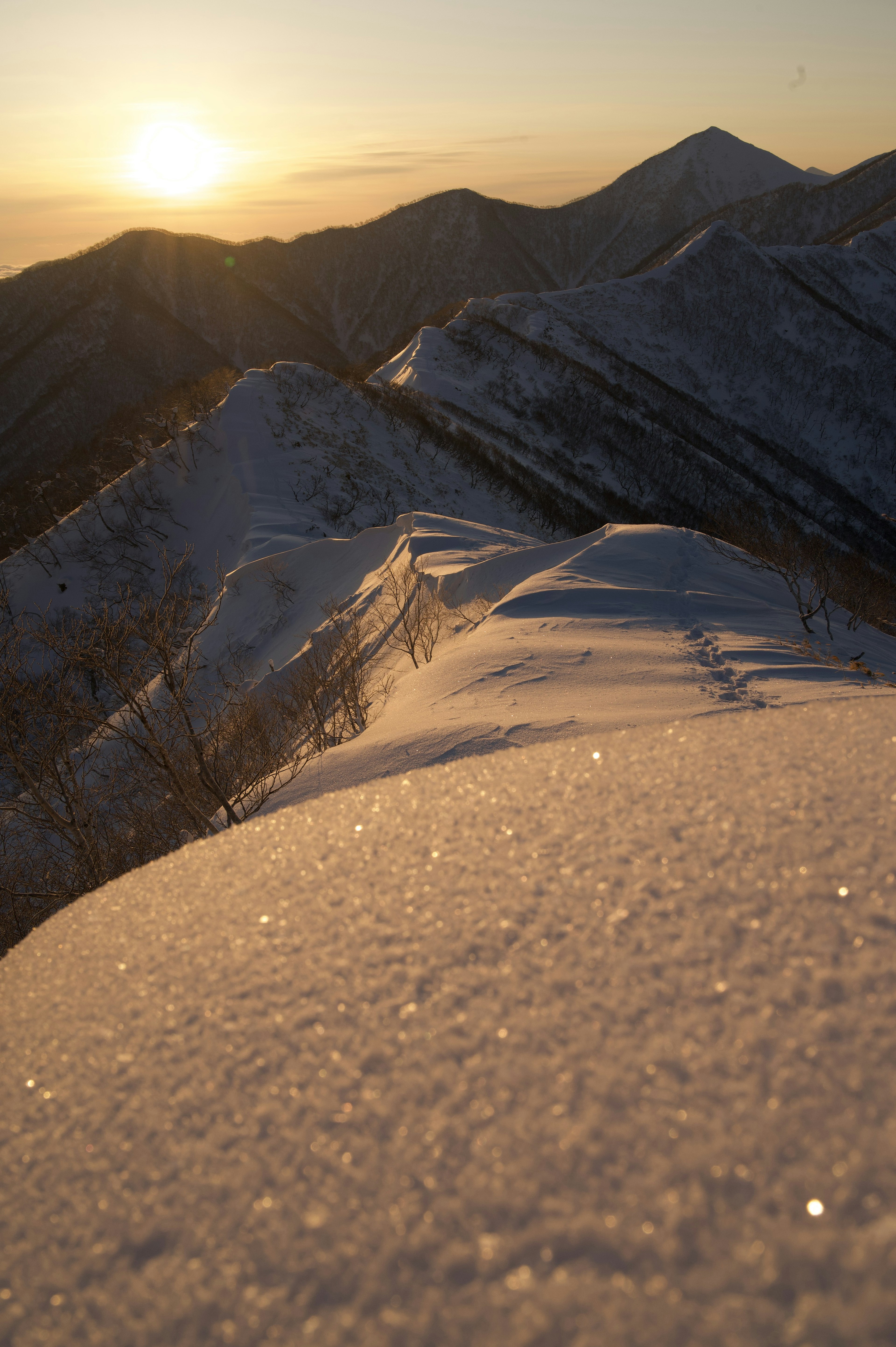 雪に覆われた山の頂上からの夕日と風景