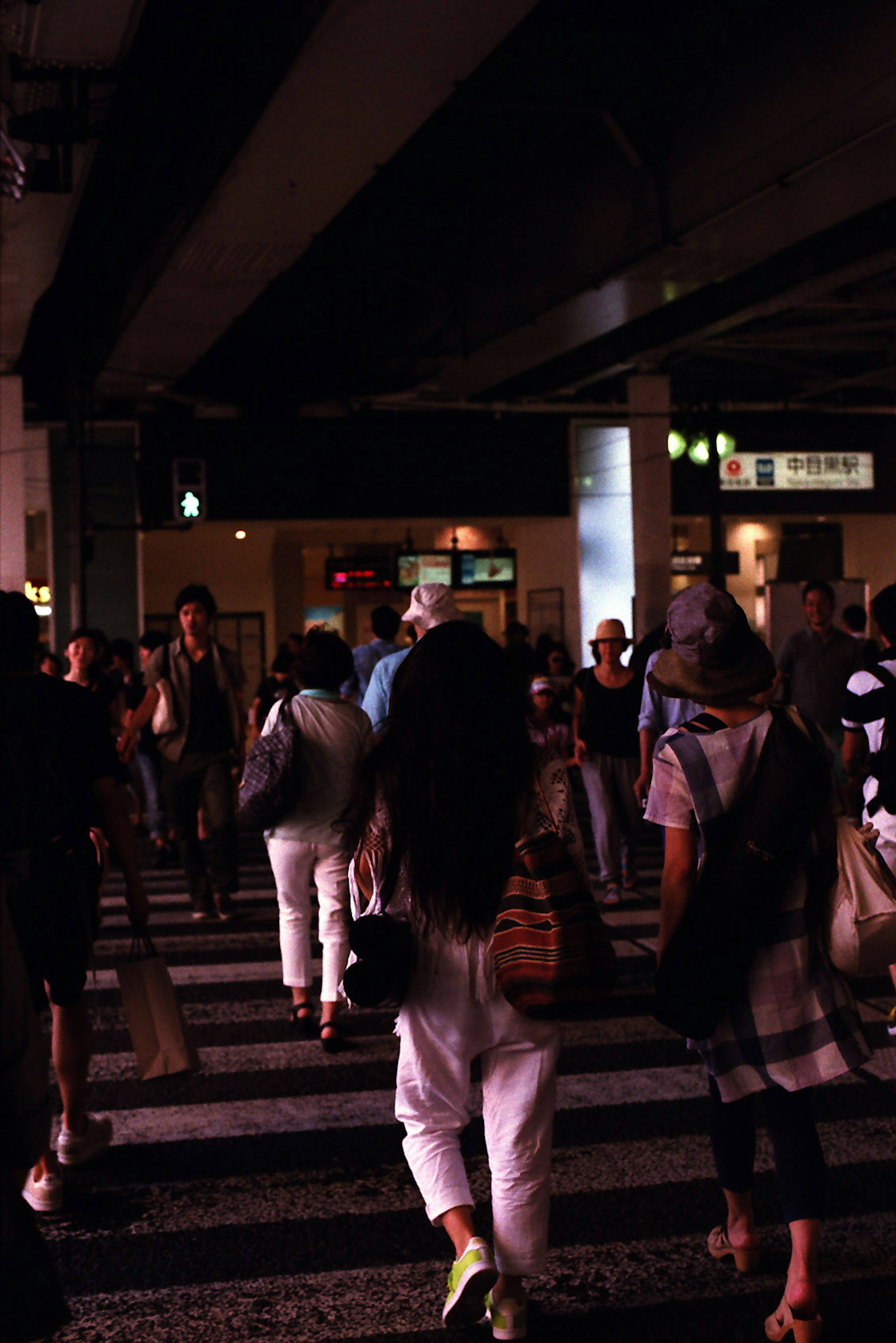 Des gens traversant une rue dans une ville la nuit