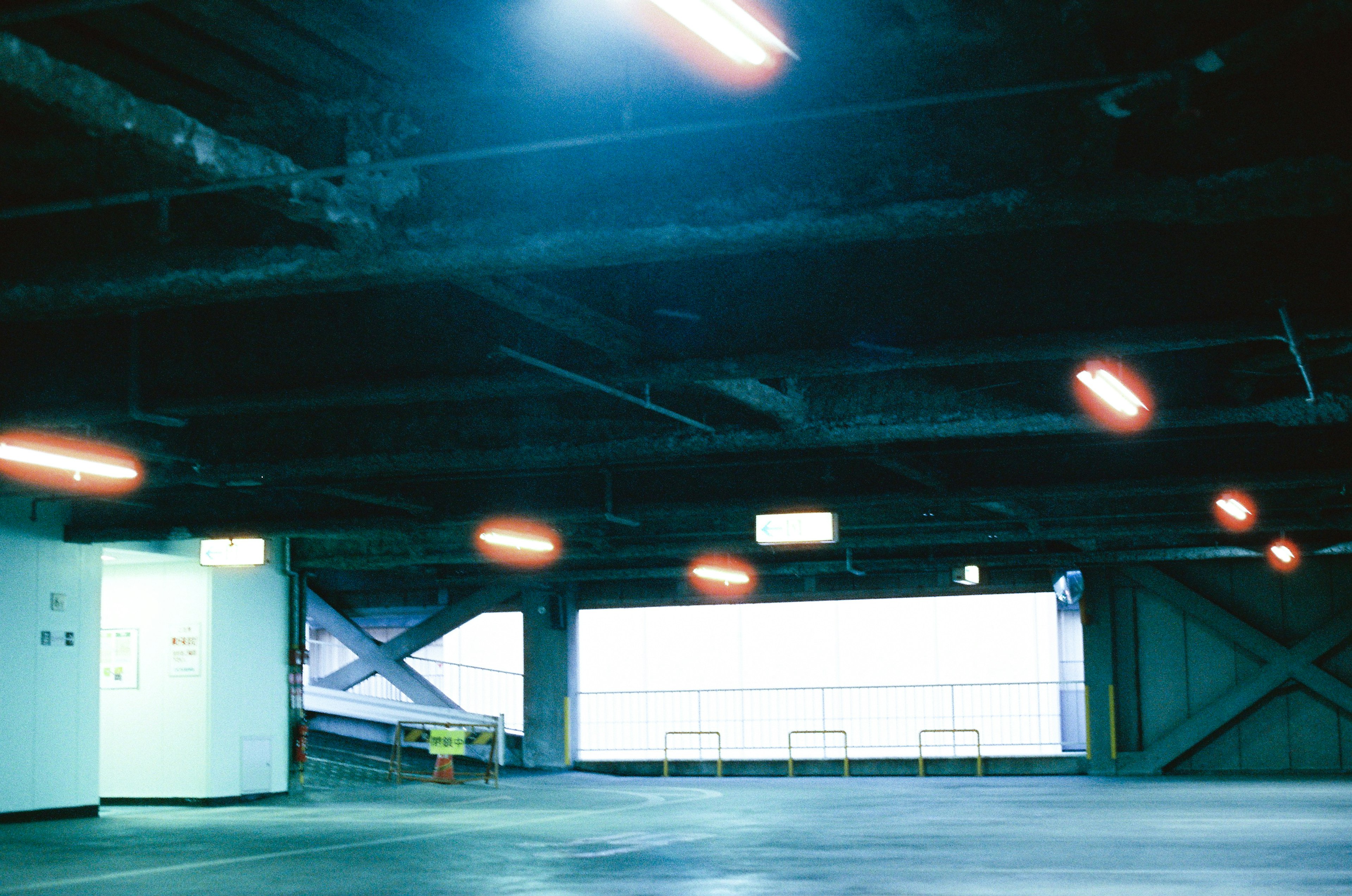 Interno di garage sotterraneo poco illuminato con illuminazione blu e struttura metallica