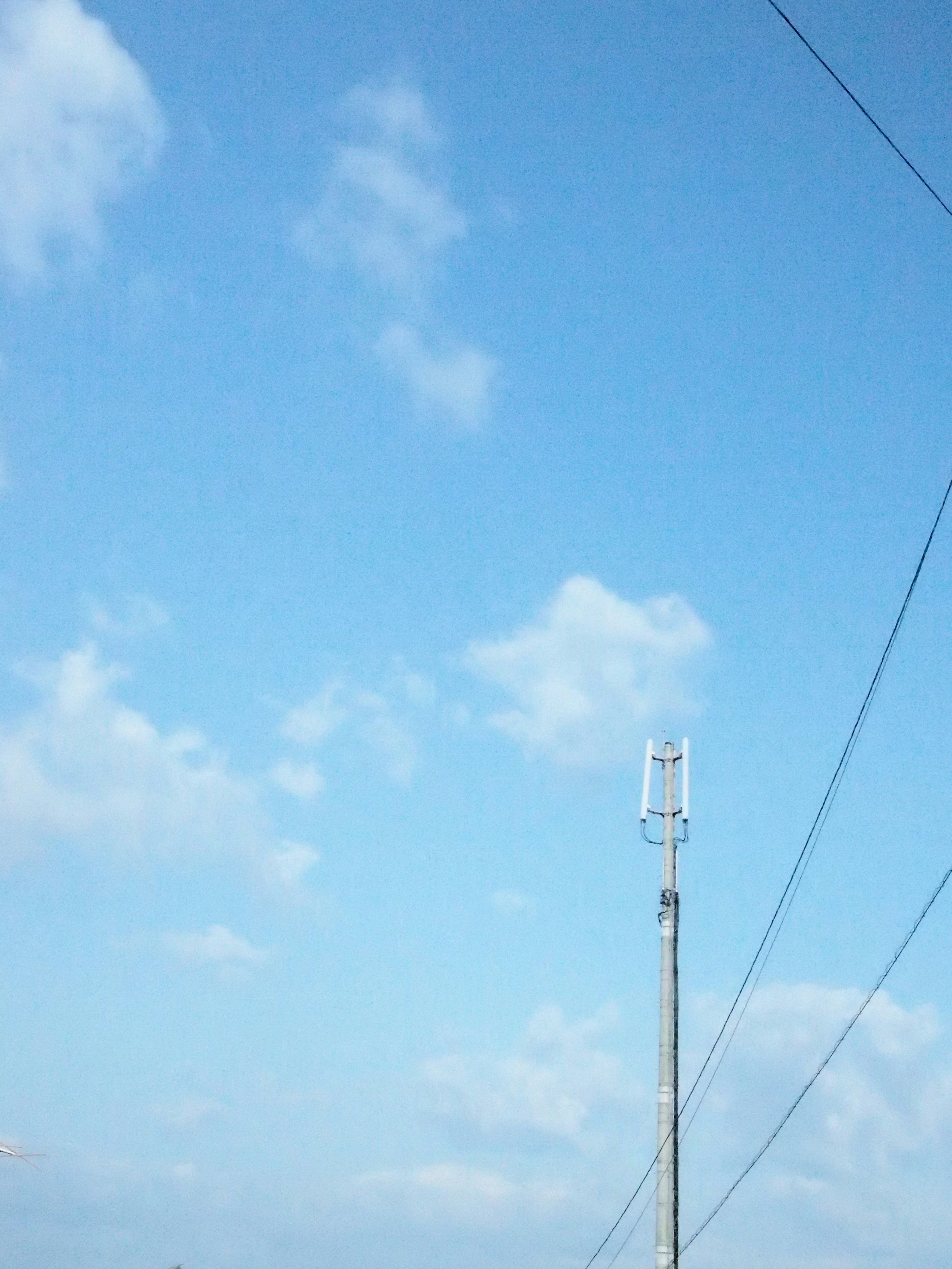 Un paesaggio con cielo blu, nuvole bianche e un palo della luce