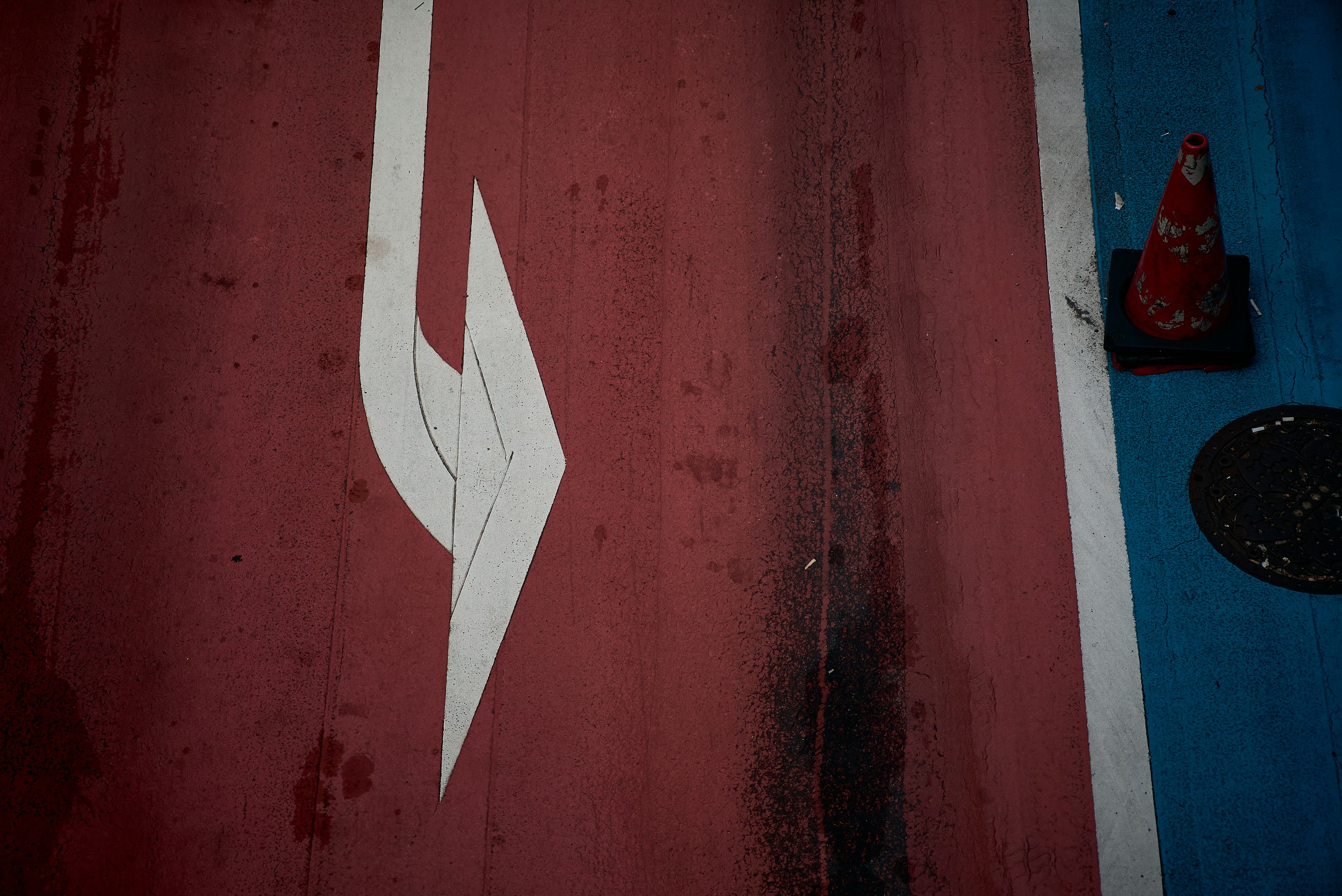 A white arrow marking on a red and blue road surface