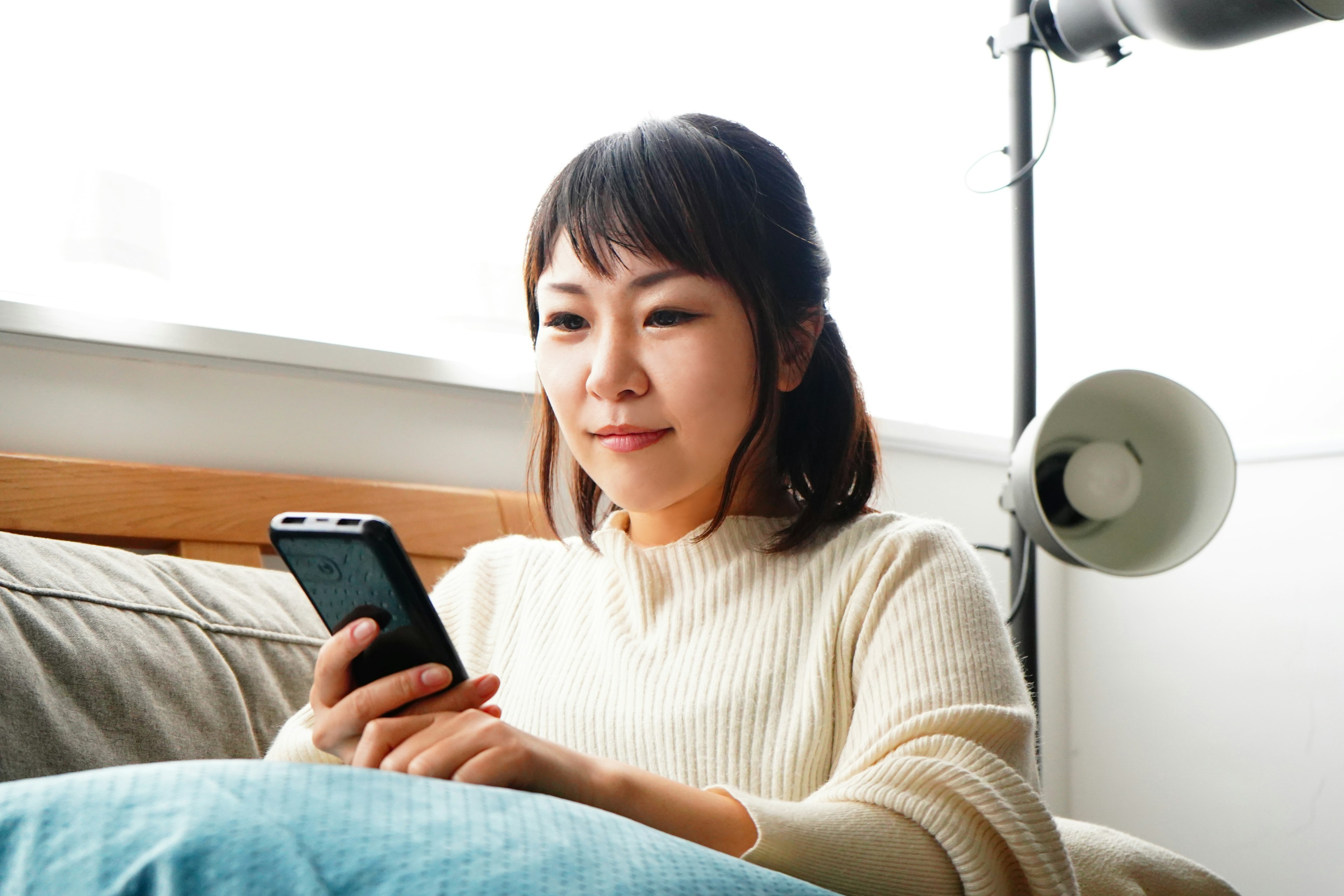 Una mujer sentada en un sofá mirando su teléfono inteligente