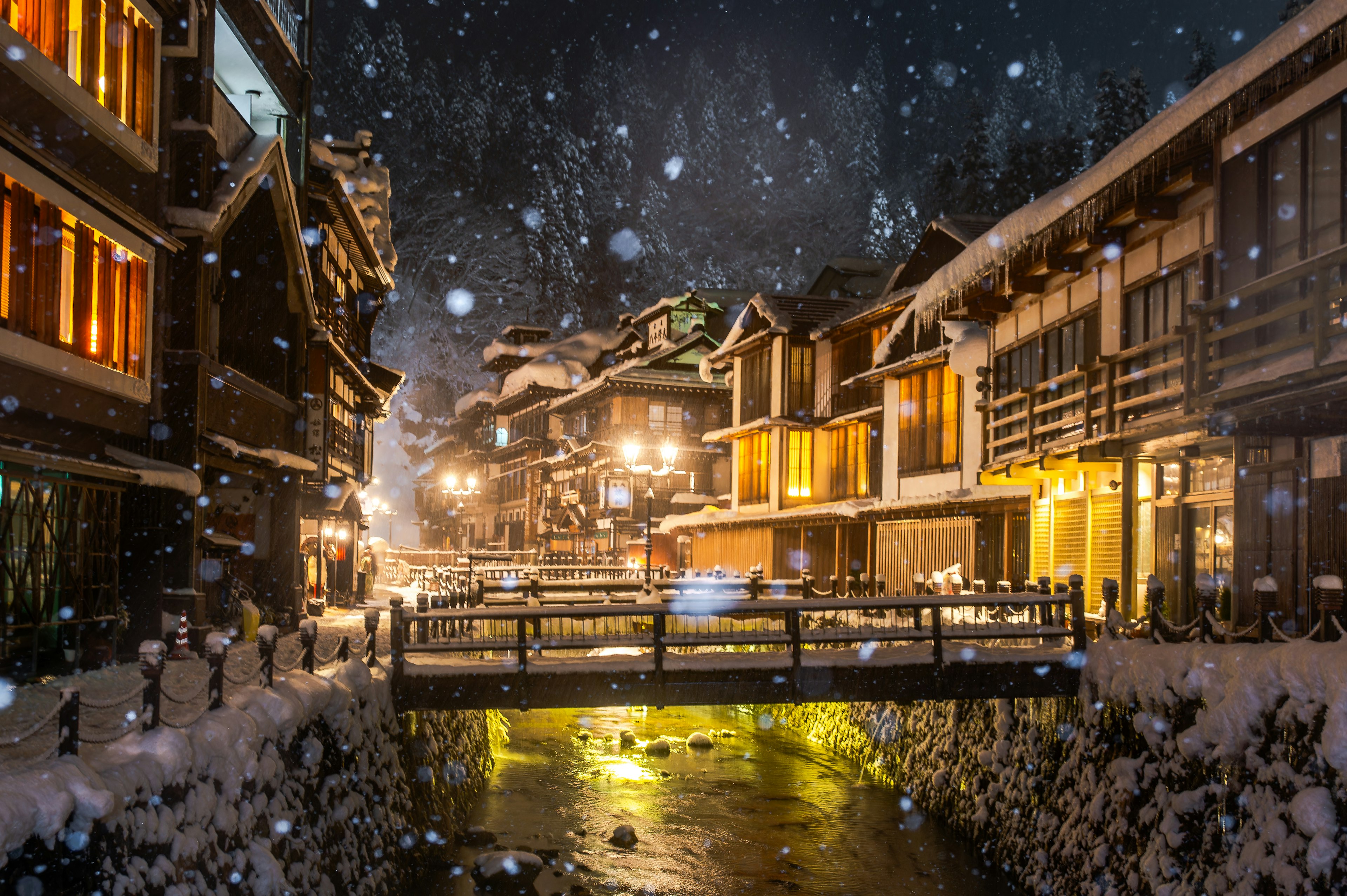 雪に覆われた街並みと温かい光の窓が印象的な夜の景色