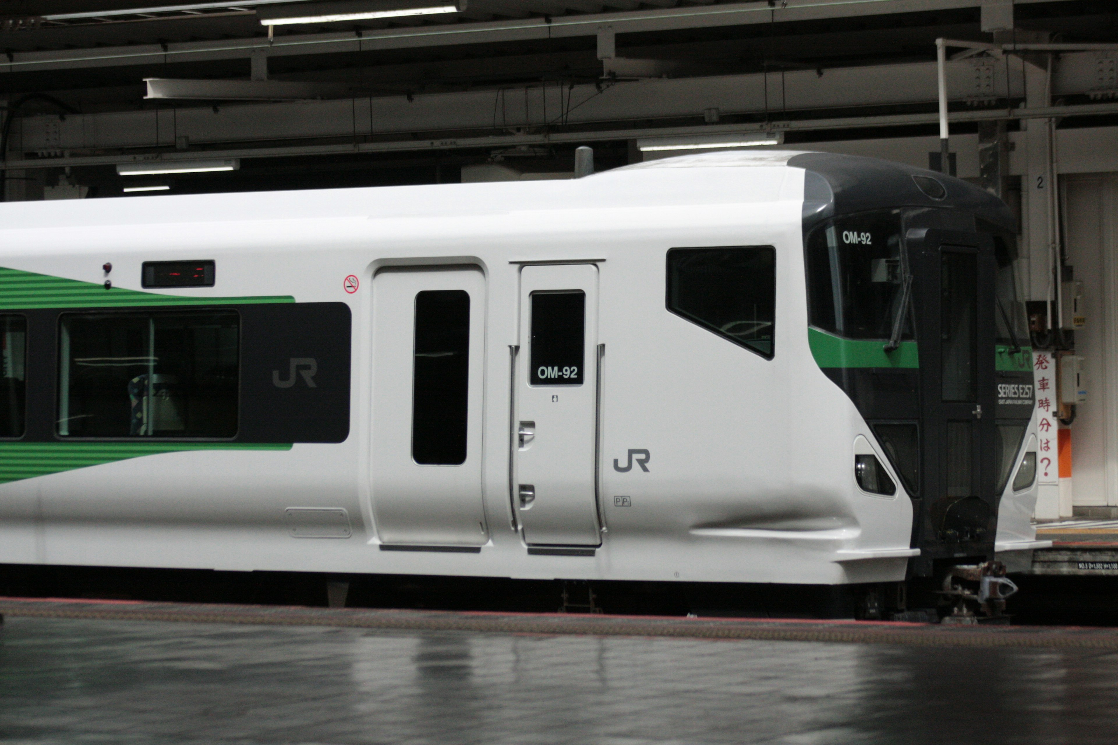 A white and green JR train parked at a station