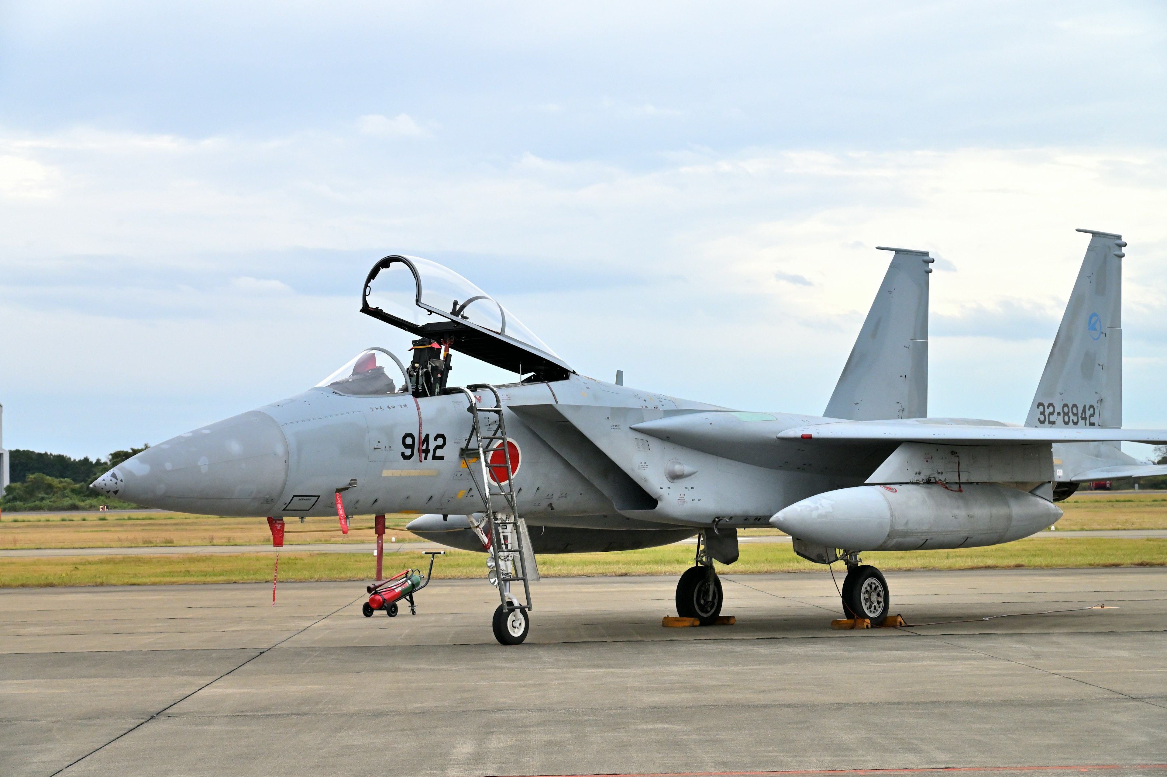 戦闘機が滑走路に停まっている風景 機体はグレーで日本の航空自衛隊のマークがある