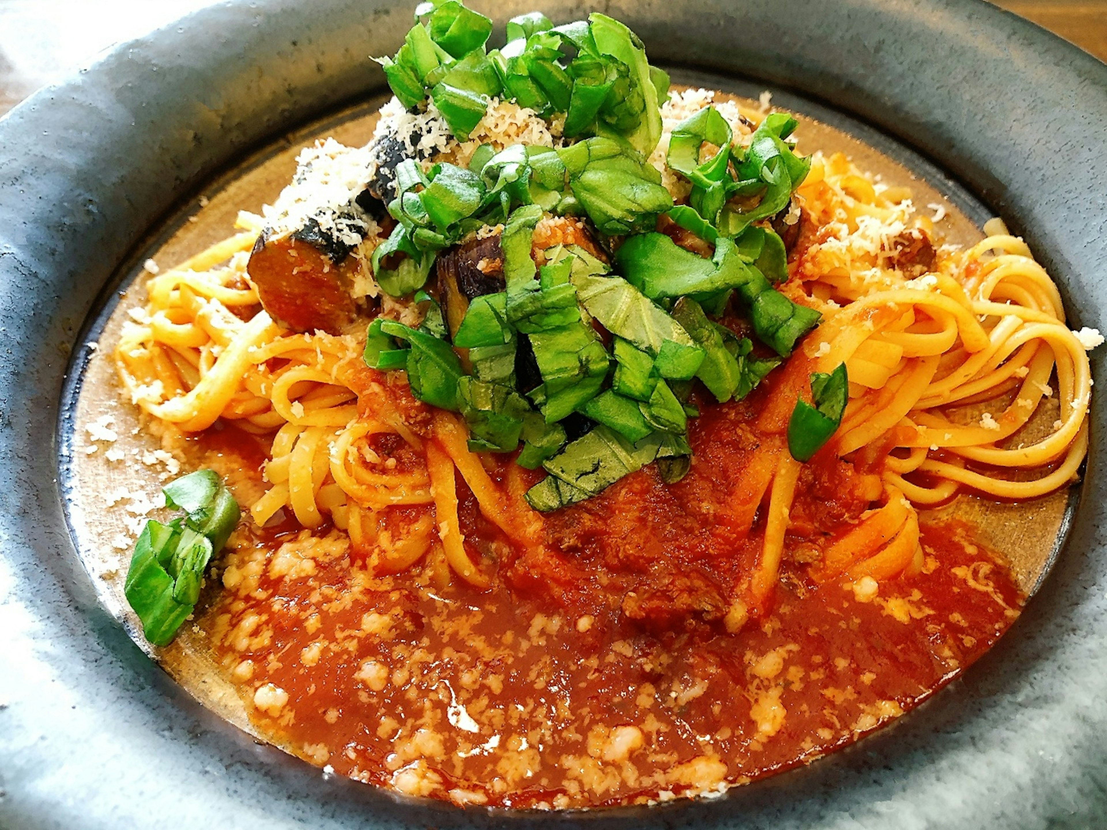 Teller mit Spaghetti, garniert mit frischen Frühlingszwiebeln und Kräutern in einer reichen Tomatensauce